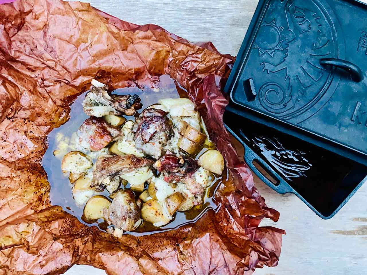 Une feuille de papier kraft avec le kleftiko dedans et sur le côté une casserole en fonte.