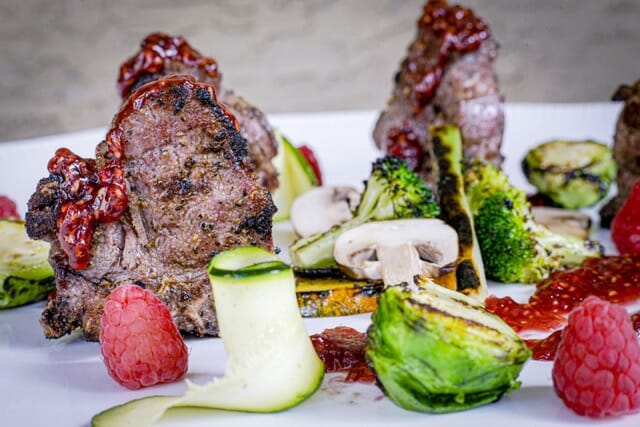 Côte d'agneau grillées, légumes verts et framboises, sauce à la framboise.