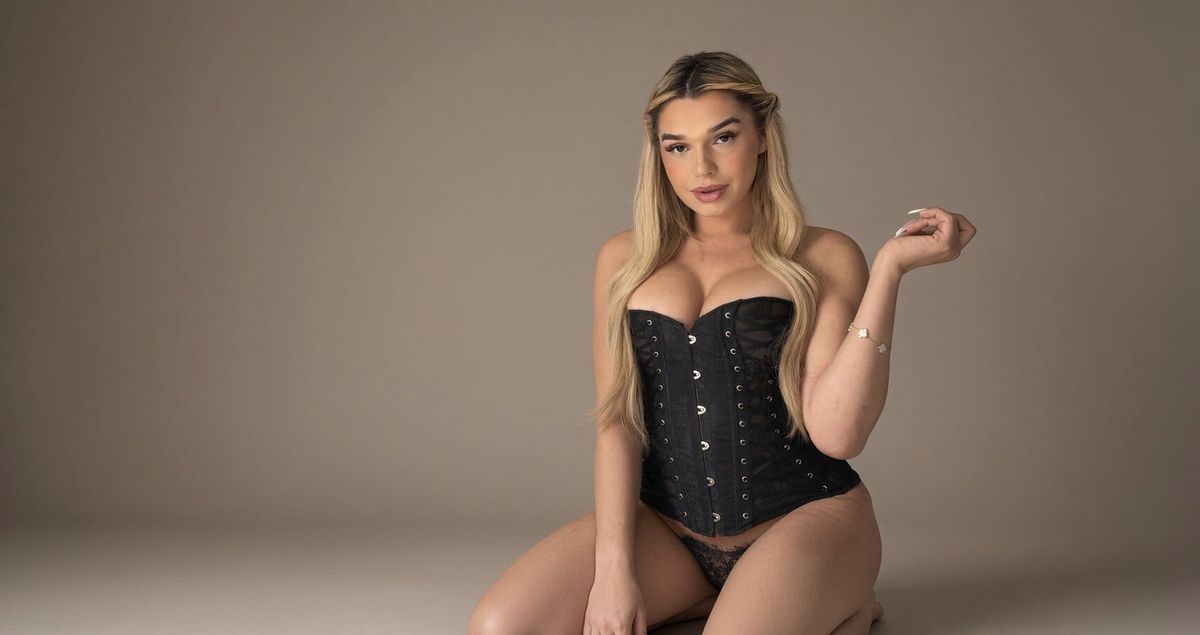 Deja seated in a black lace corset under studio light