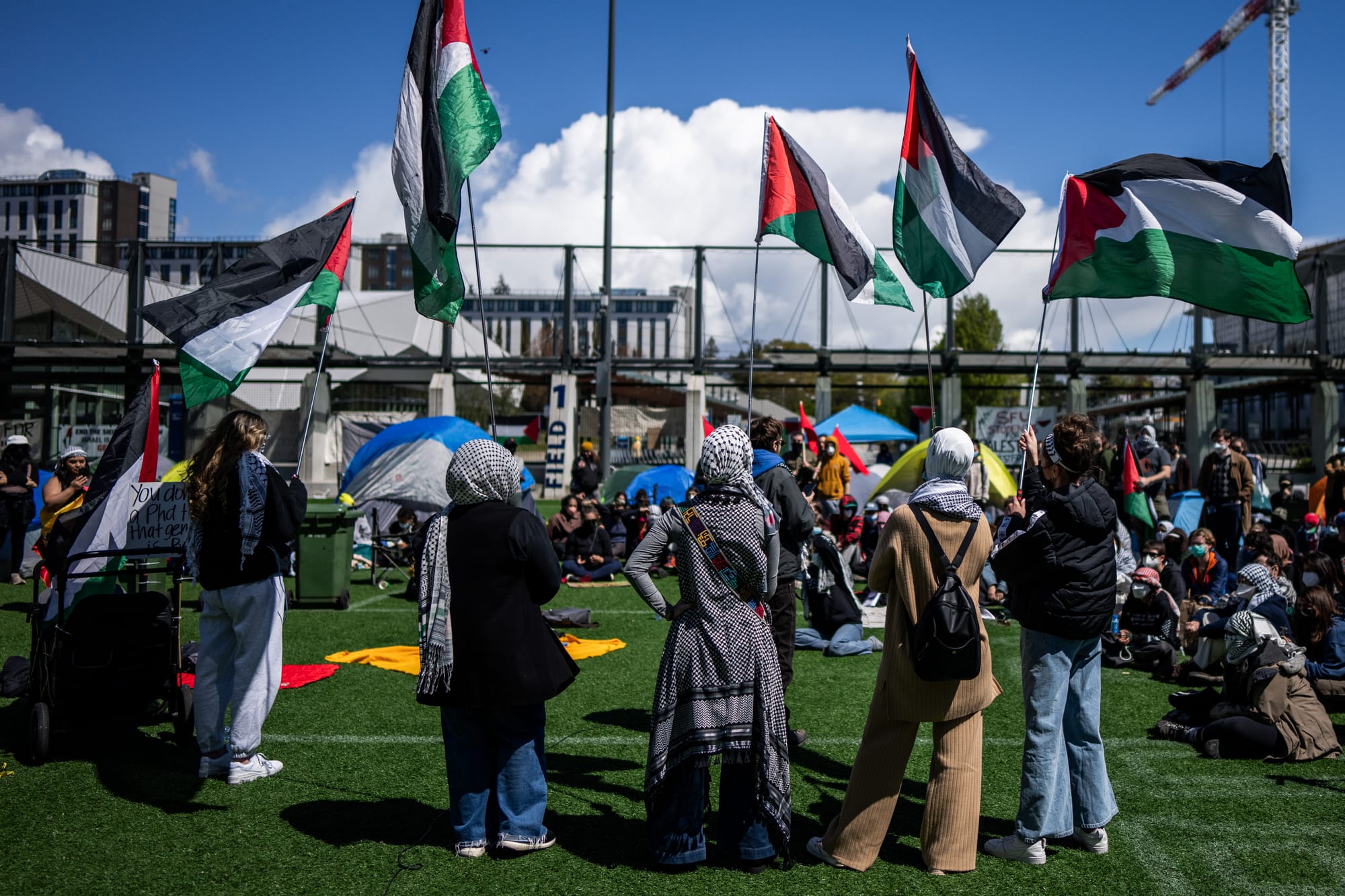 People wave flags during a student encampment for Palestine at the University of British Columbia campus in Vancouver on April 29, 2024.