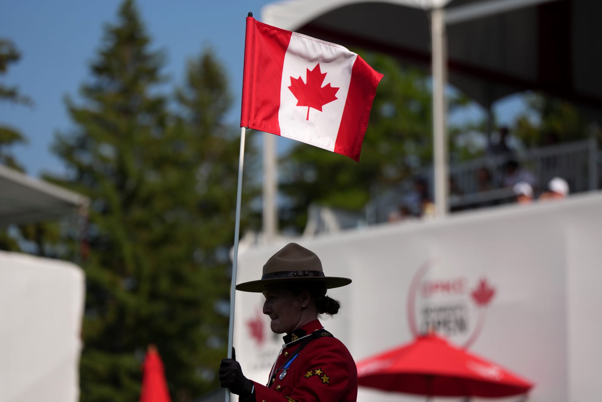 An RCMP officer holds the 18th hole flag stick, bearing the Canadian flag, during the LPGA CPKC Canadian Women's Open golf tournament in Edmonton in August. (The Canadian Press/Darryl Dyck)