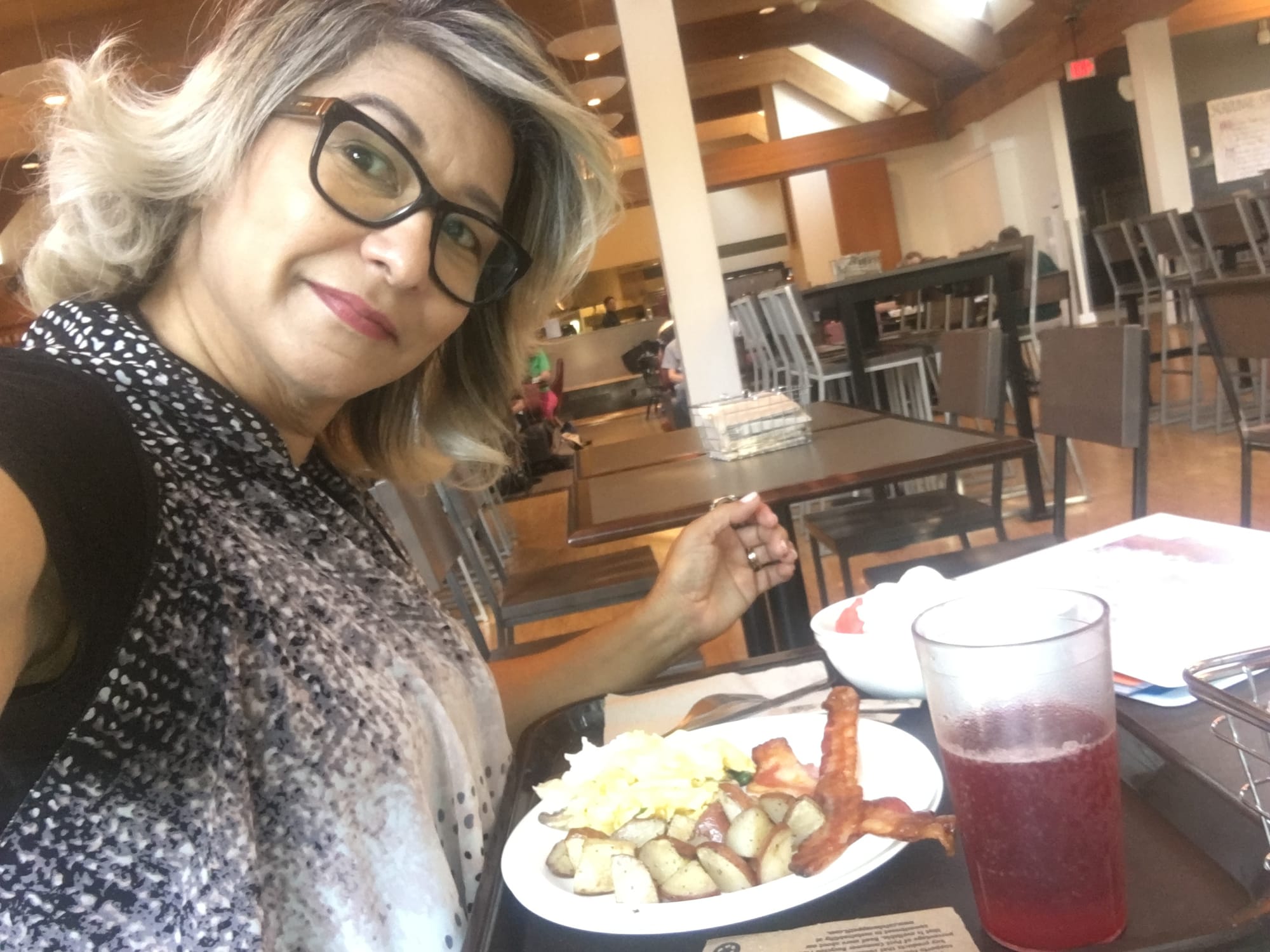 Hilda Peguero sentada en la cafetería de Reed College frente a un desayuno servido en plato de loza, con vaso reutilizable y cubiertos de metal.
