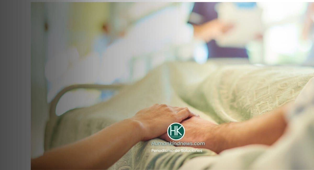 Mano de una enfermera sobre la de una paciente en cama, con luz suave de mañana