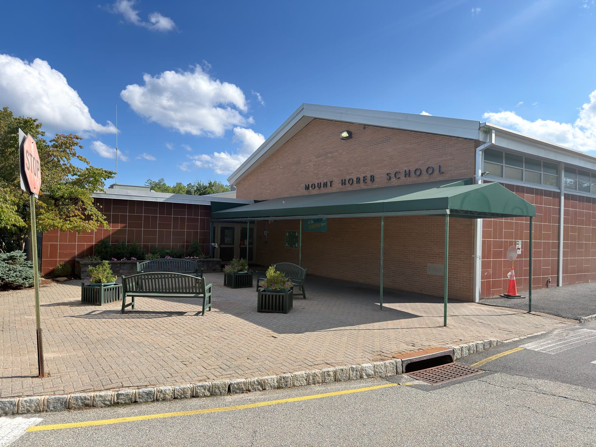 Mount Horeb School in Warren Township, a brick elementary building with MOUNT HOREB SCHOOL lettered on the gable, a green canopy over the entrance walk and benches on a paver courtyard.