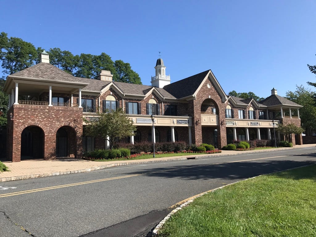 The NextHome Premier office at 102 Town Center Drive in Warren, a two story brick building with a white cupola behind it and the NextHome sign over the entrance.