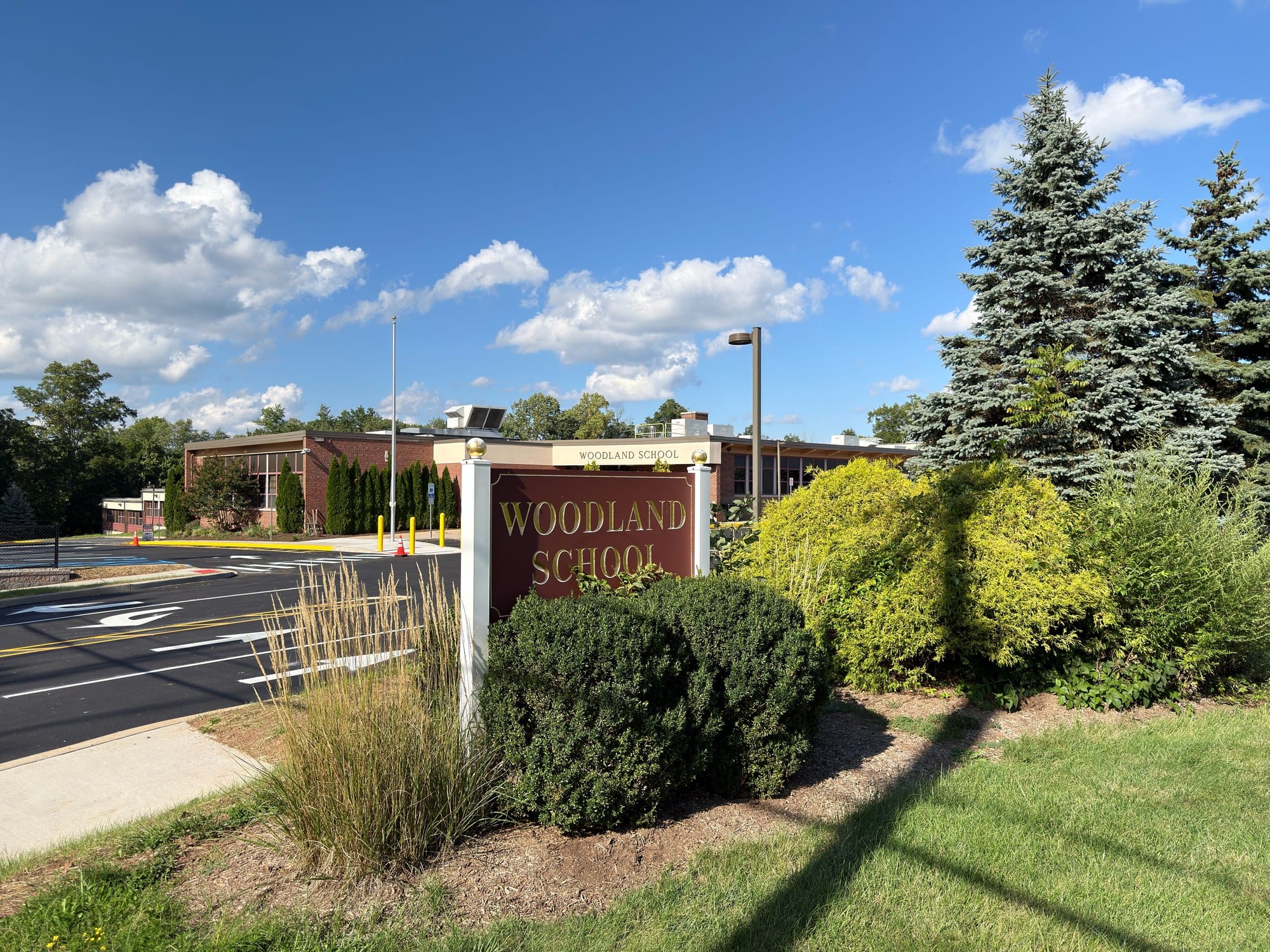 Woodland School in Warren Township, a low brick building with WOODLAND SCHOOL lettered over the entrance and a maroon and gold monument sign carrying the same name at the parking lot edge.
