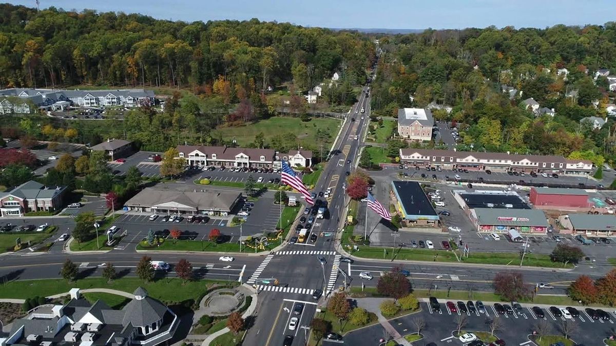 Aerial view of the Warren Township town center intersection, showing shopping centers, parking and surrounding wooded neighbo