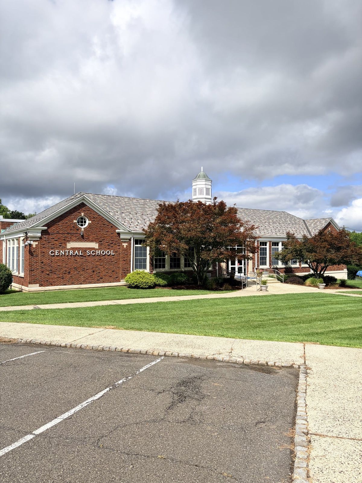 Central School in Warren Township, a brick elementary school with a white cupola, lettering reading Central School over the entrance and a mown lawn in front.