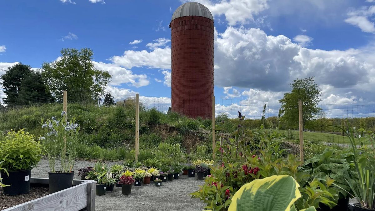 The red silo at Wagner Farm Arboretum in Warren, with potted plants and garden beds in the foreground.