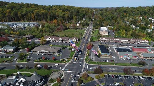 Aerial view of the Warren Township town center intersection, showing shopping centers, parking and surrounding wooded neighbo