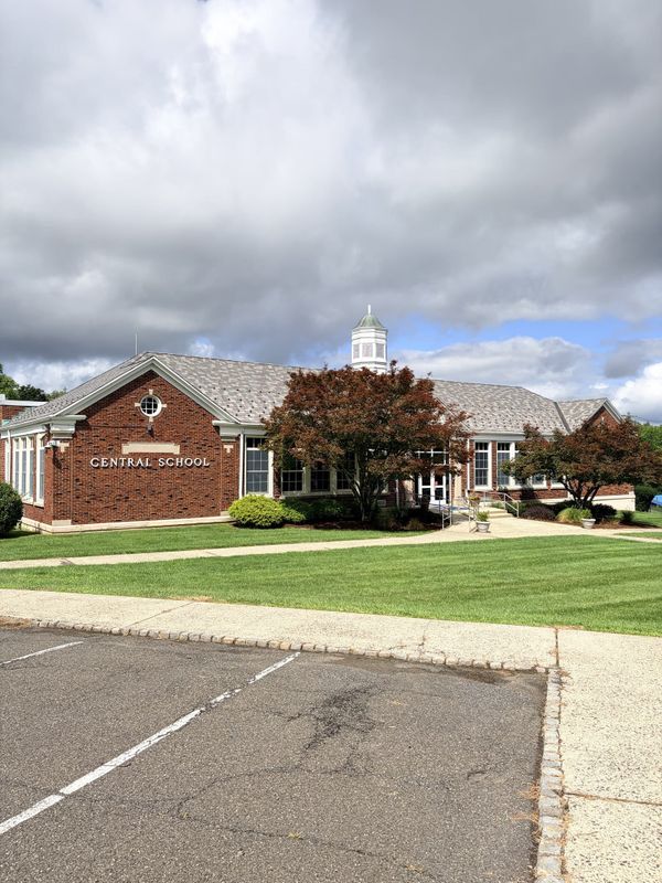 Central School in Warren Township, a brick elementary school with a white cupola, lettering reading Central School over the entrance and a mown lawn in front.
