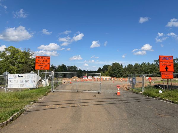 A chain link gate closed across the construction drive at 15 Mountainview Road in Warren Township, under a Restricted Access Construction Vehicles Only sign.