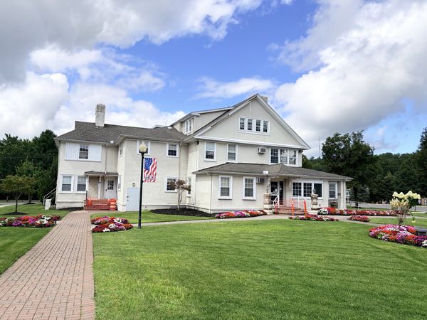 The Hofheimer House at the Warren municipal complex, a cream stucco former municipal building with two chimneys and dormers.