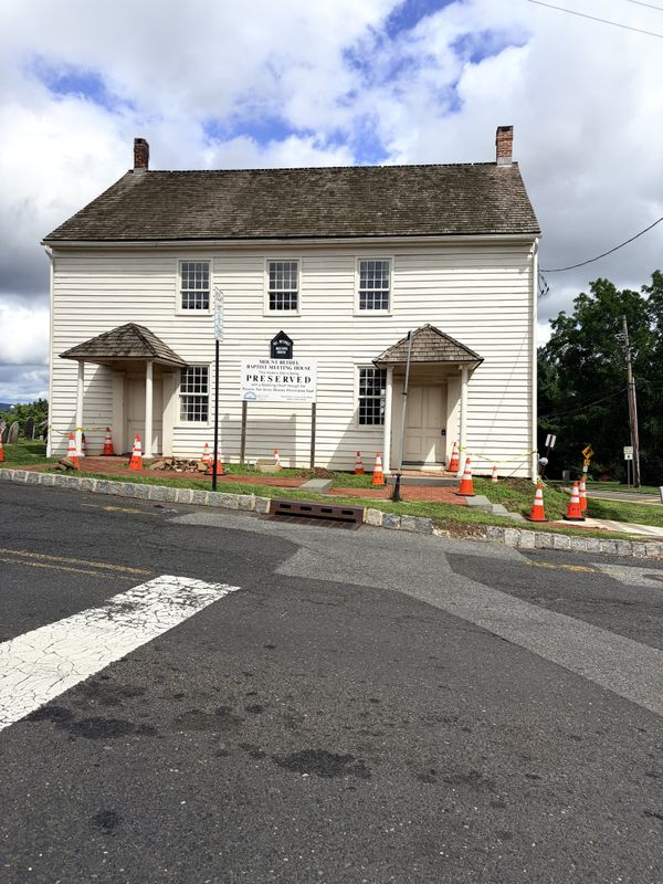 The Mount Bethel Baptist Meeting House in Warren Township, a cream clapboard building with two gabled entry porches and a preservation sign on the lawn.