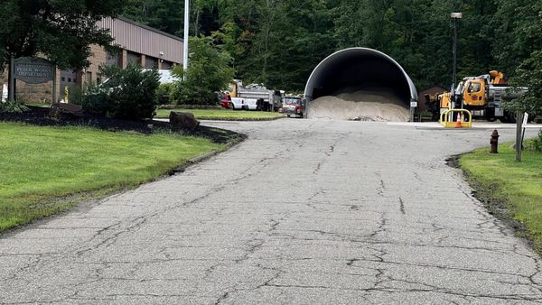 The Warren Township Public Works facility on Bardy Road, with the department sign and flagpole at left, a sand and salt storage dome ahead, and department trucks parked alongside.