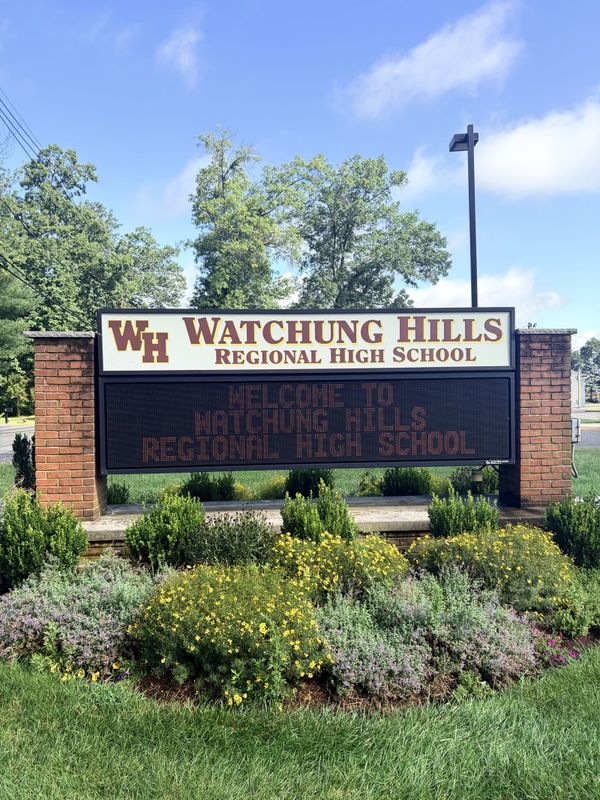 The Watchung Hills Regional High School sign, a brick and white sign with the maroon WH monogram above an electronic message board reading Welcome to Watchung Hills Regional High School.