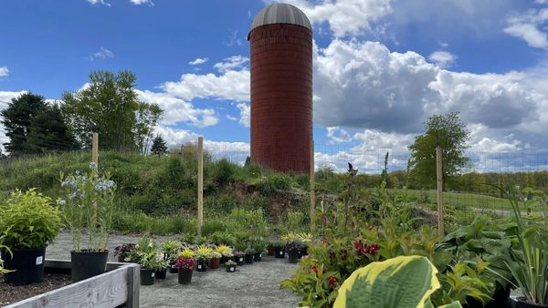 The red silo at Wagner Farm Arboretum in Warren, with potted plants and garden beds in the foreground.