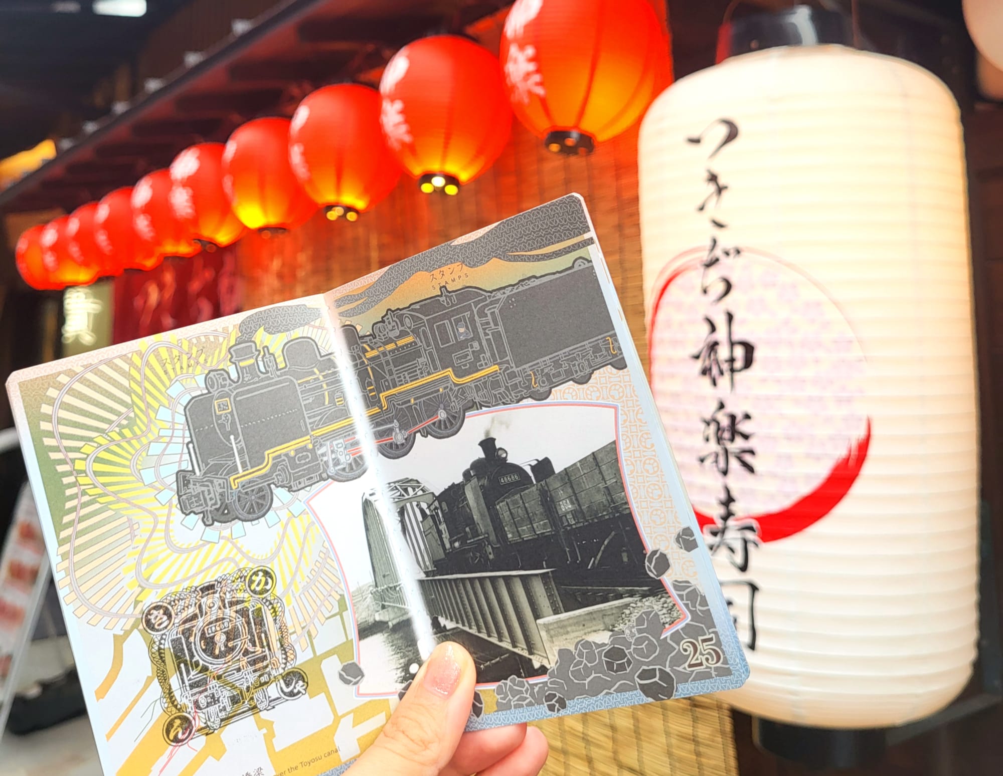 A girl holding a stamp book in front of a Japanese lantern at Tsukiji Market