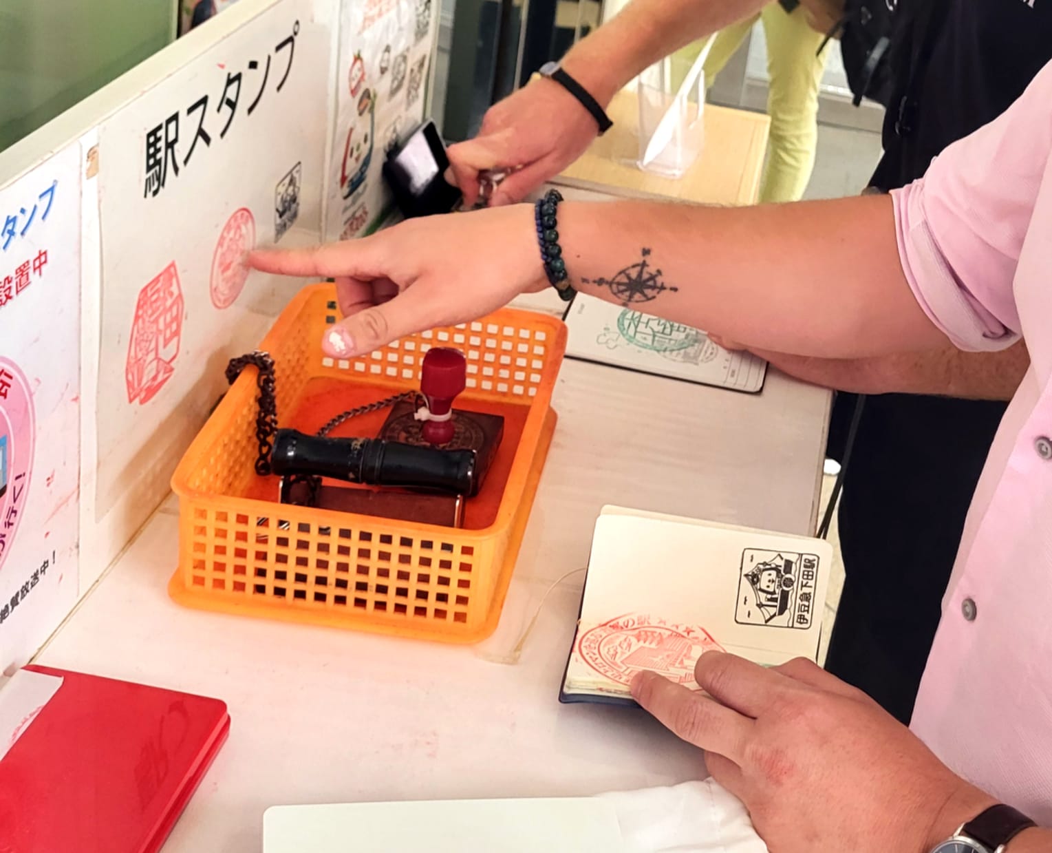 2 friends at a train station in Japan collecting train stamps with their notebooks