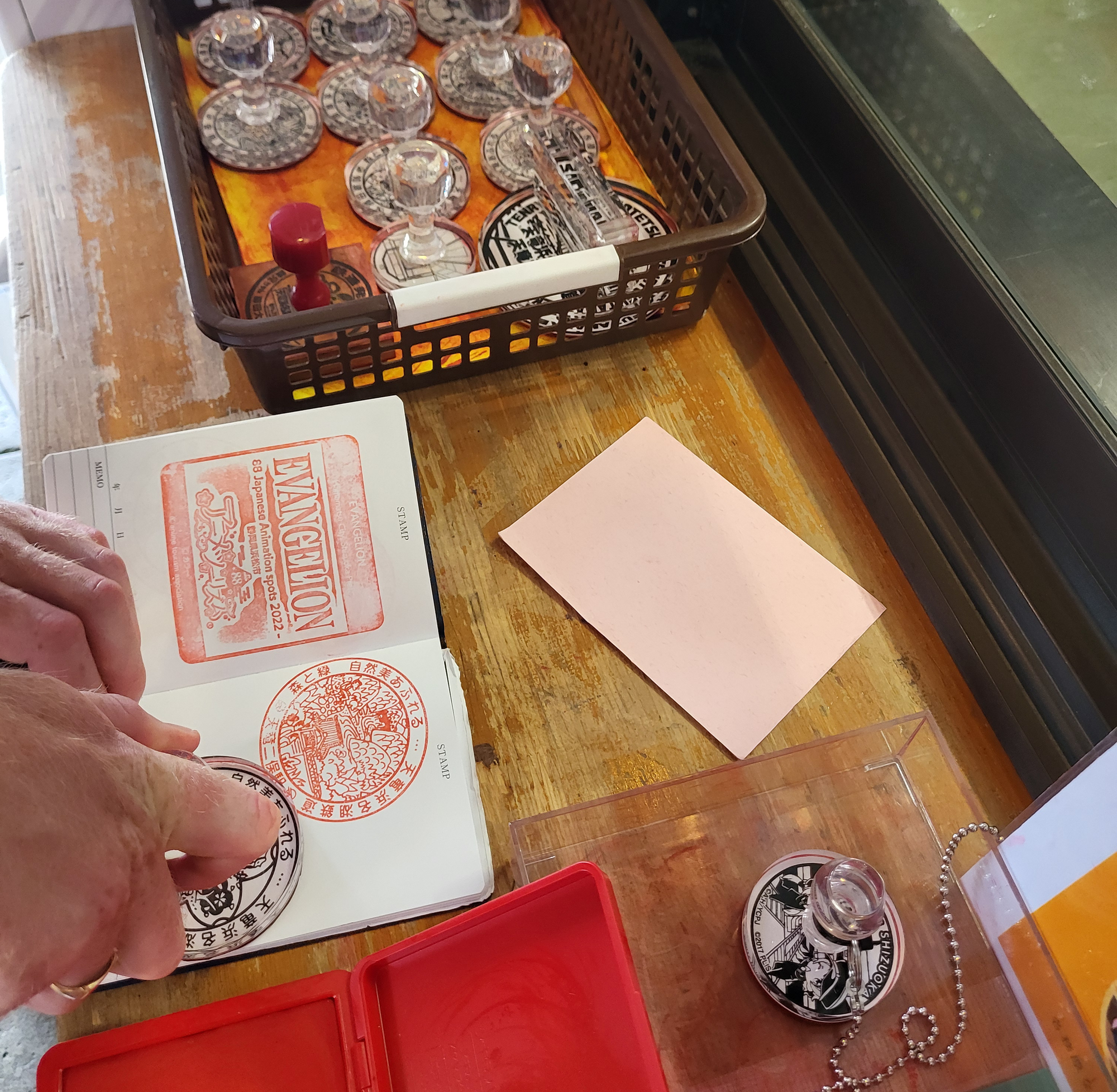 A young man stamping ink stamp on their notebook next to a plastic basket full of stamps.