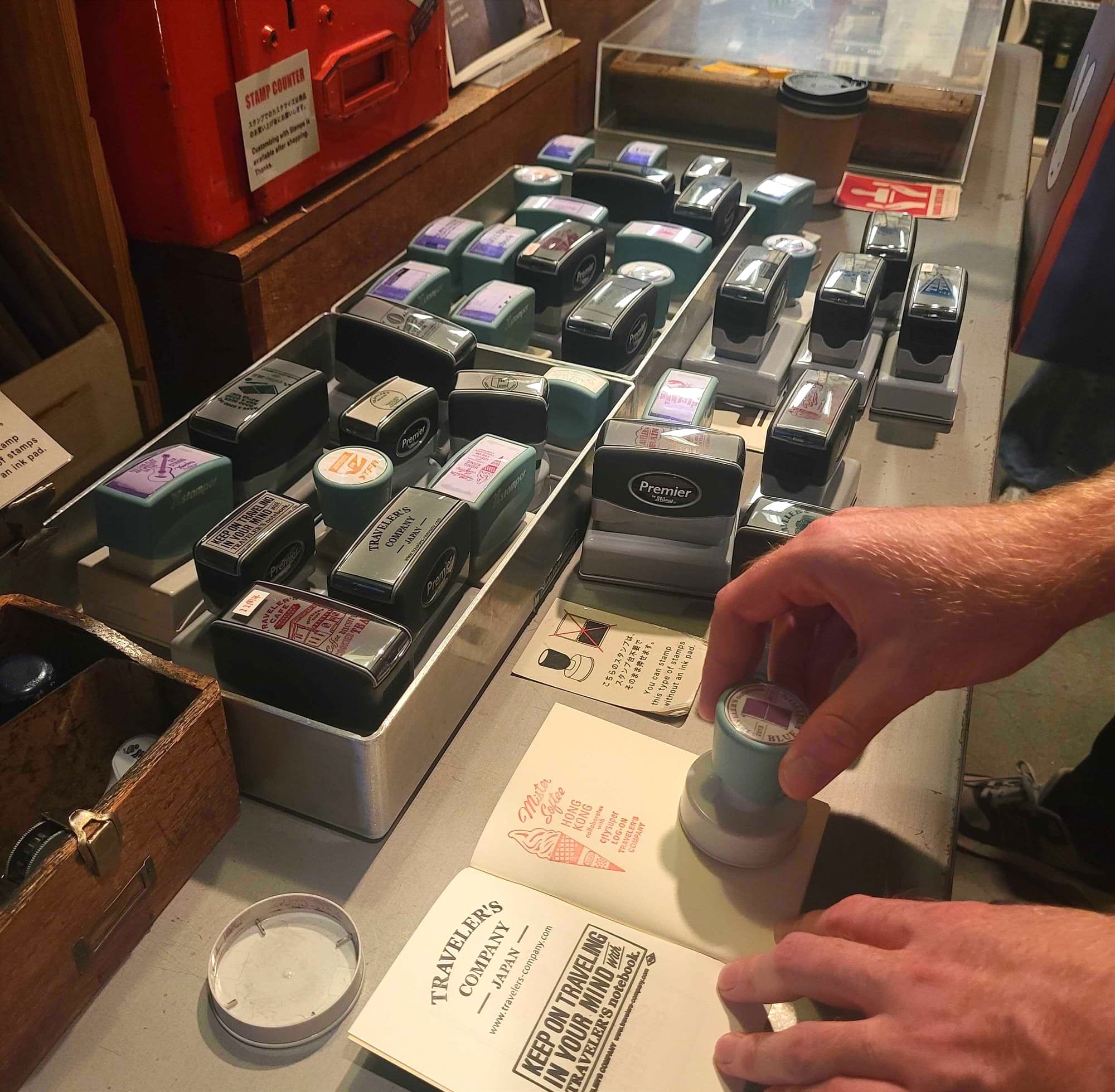 A young man stamping ink stamps on his notebook at a store full of ink stamps