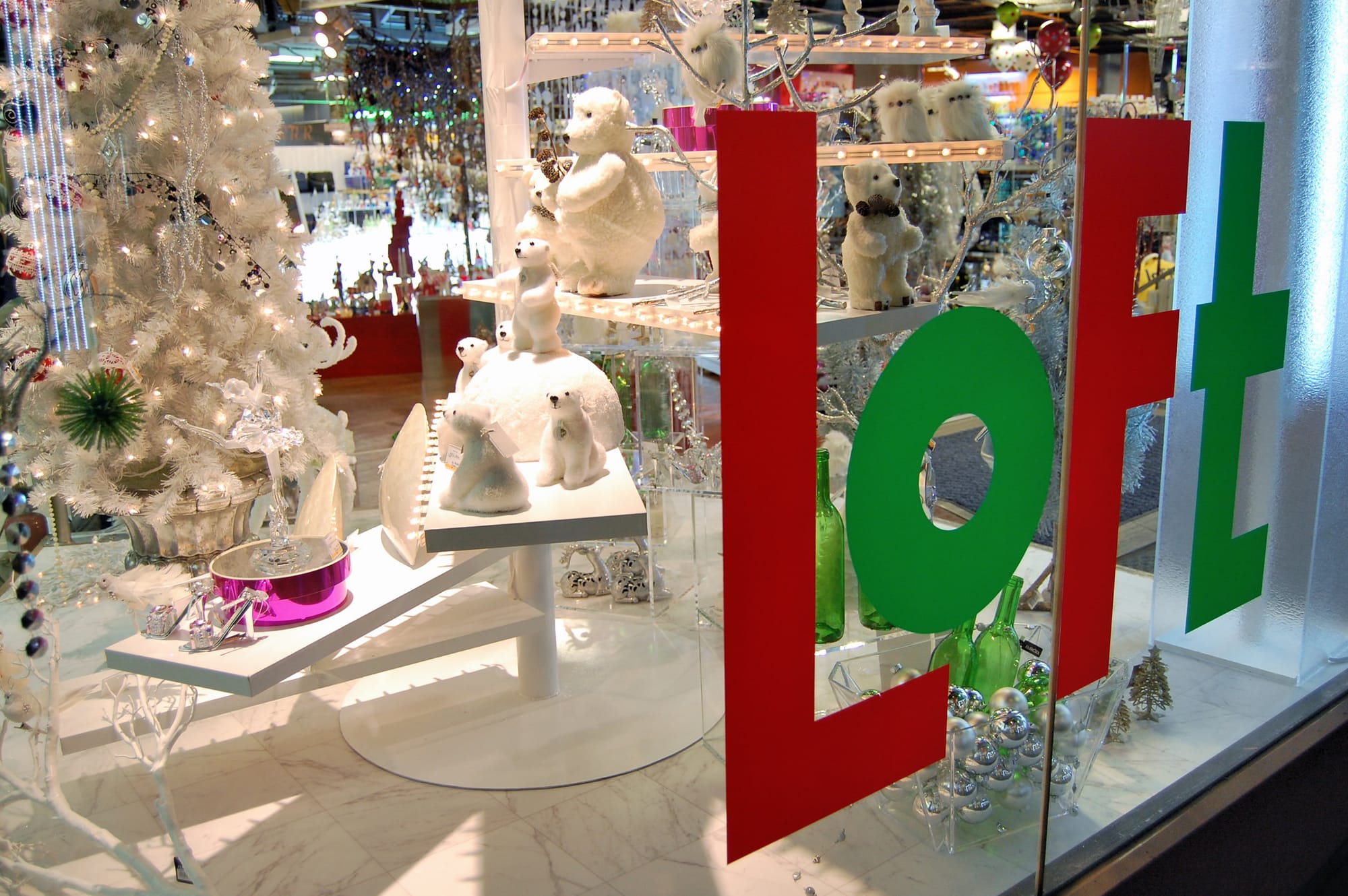 Holiday-themed window display with white polar bear figurines, a sparkling white tree inside the LOFT store.