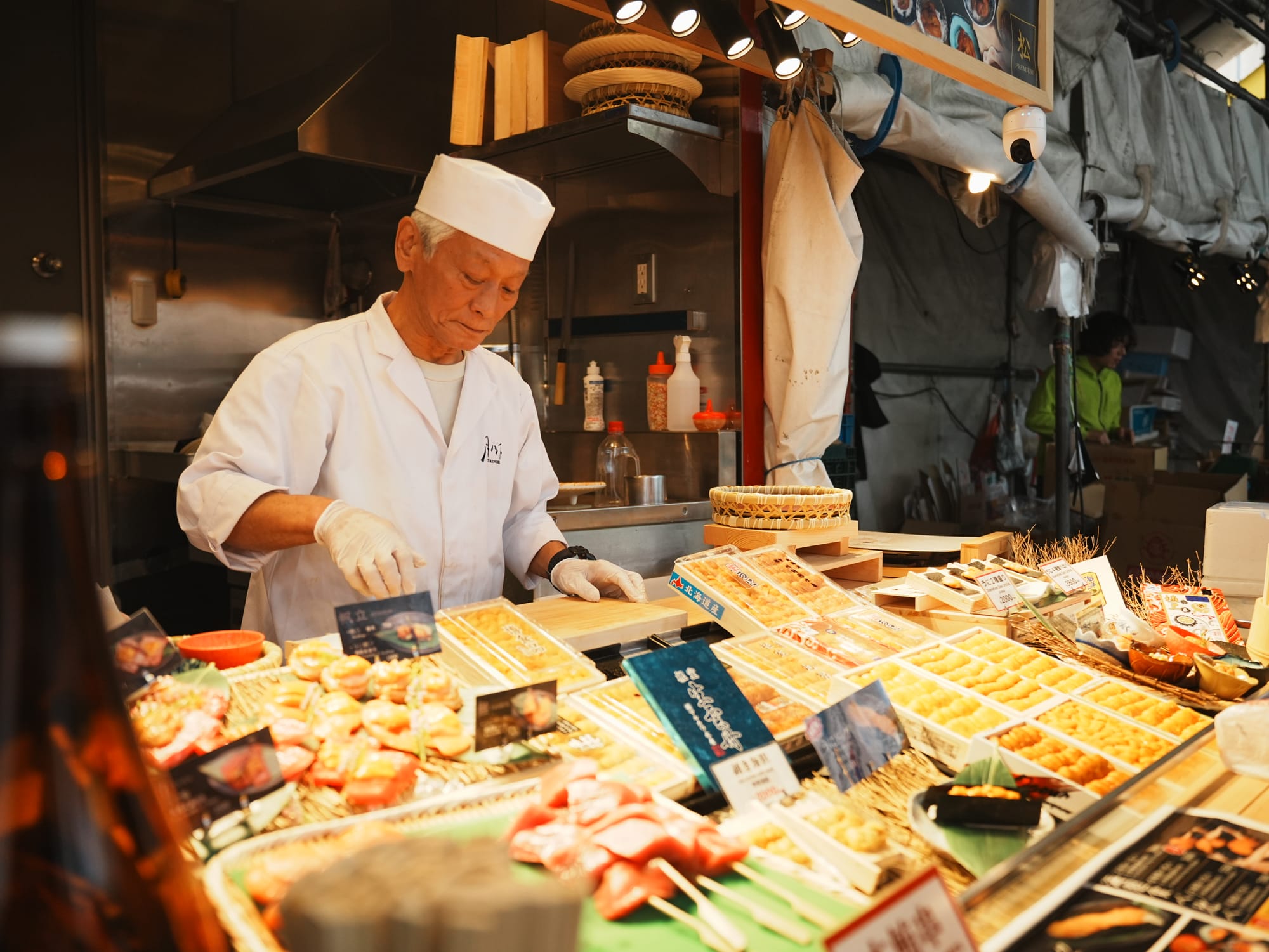 Vendor in white uniform sells food at a vibrant market stall