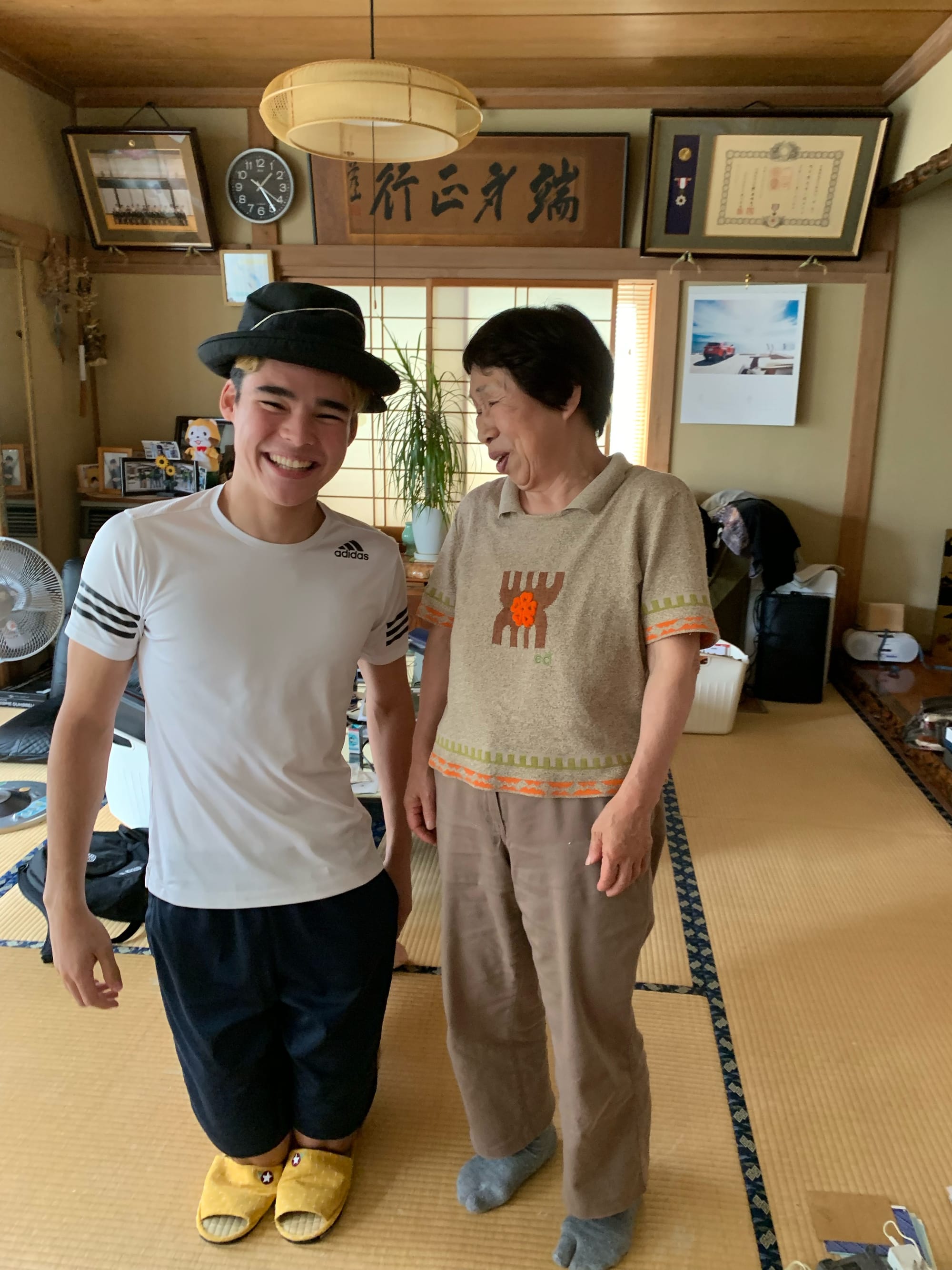 A young Japanese man and his grandma staying in front of the camera inside a traditional Japanese house.