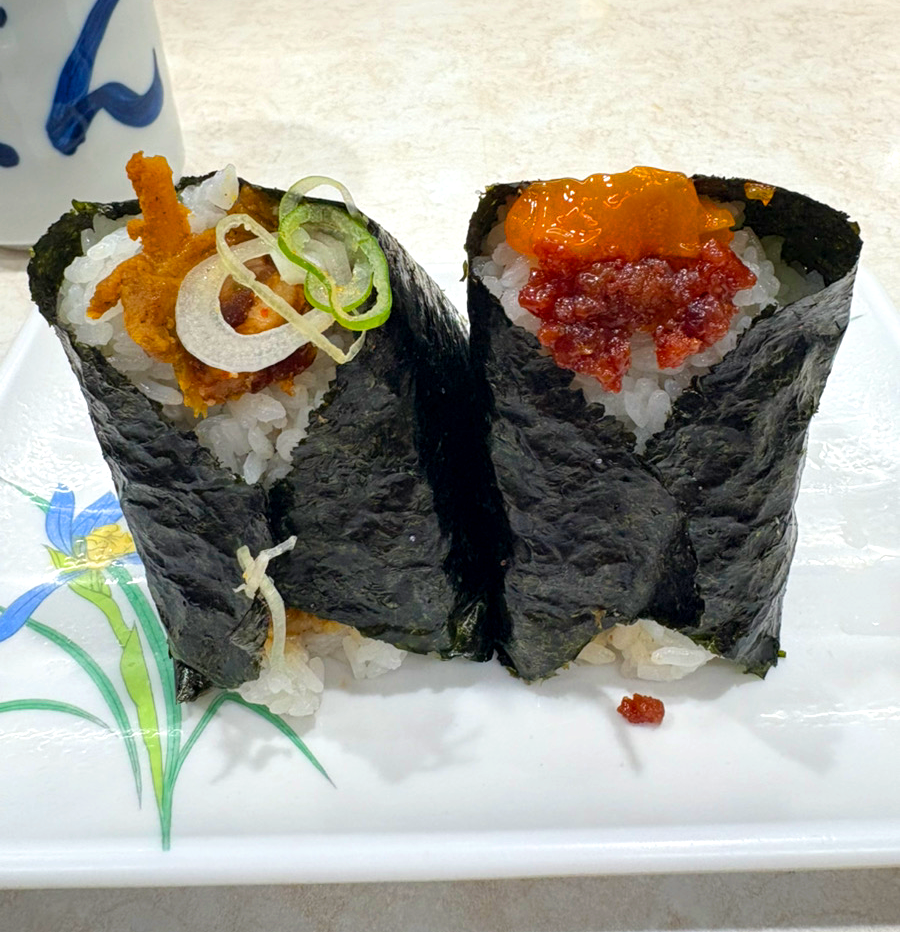 2 big onigiris filled with ingredients and a cup of green tea on the side