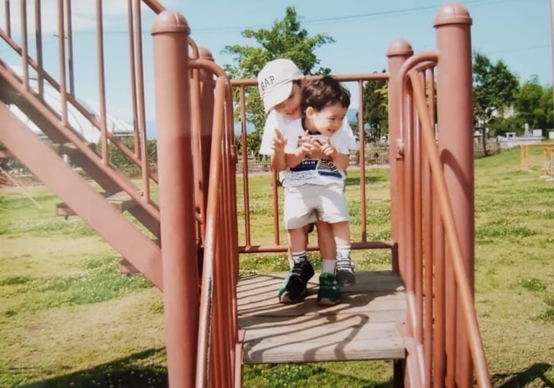 A small kid and his brother hugging and having fun at a kids playground in Japan.