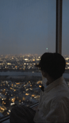 A young Japanese man looking at the city views at night from an observatory in Japan.