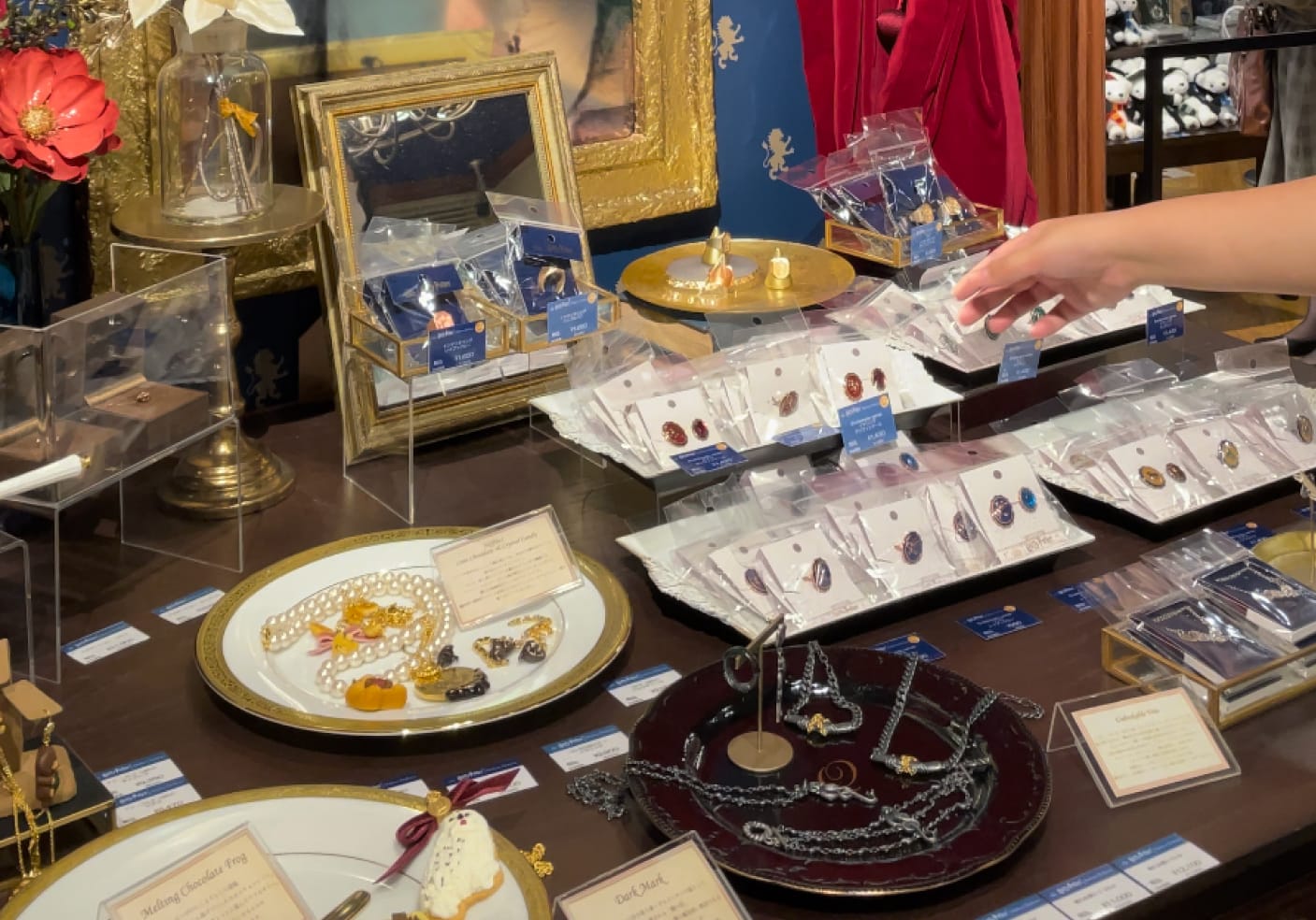 Display of jewelry, including Harry Potter Q-pot collaboration jewelry, with ornate frames and fabric in background. 
