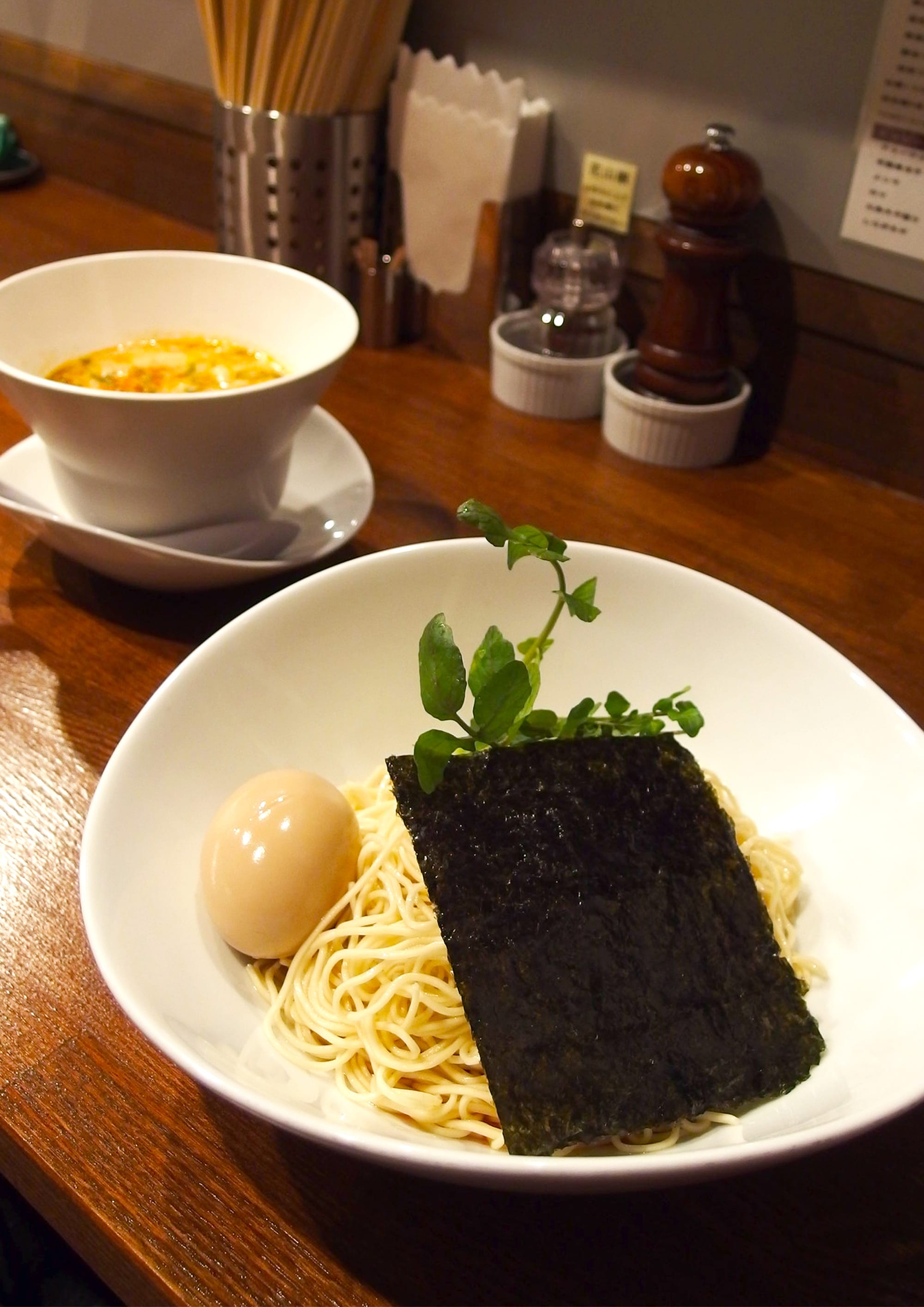 Counter at Nakiryu and a serving of tsukemen. Bowl of ramen with seaweed, ramen and egg.