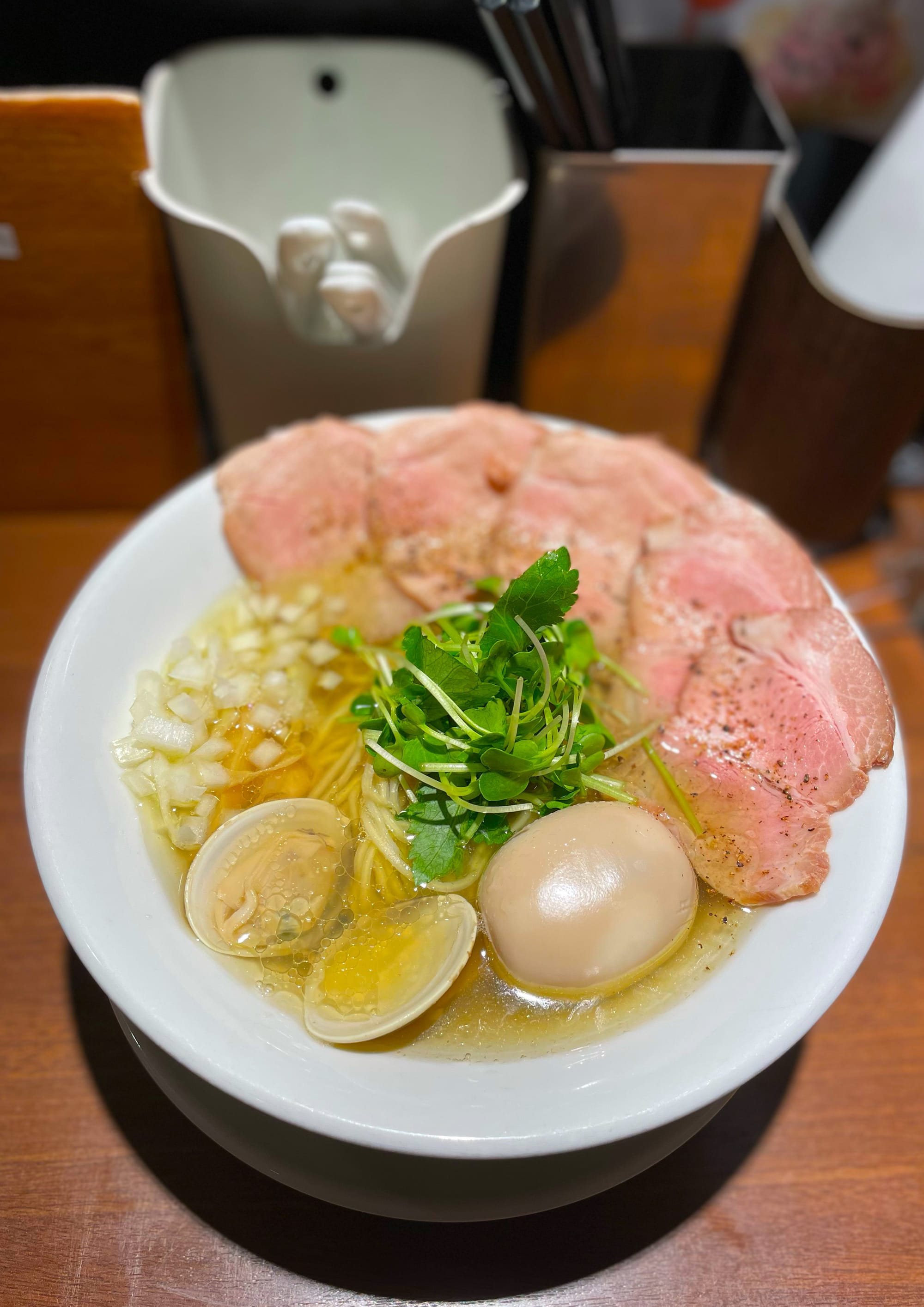 The clam soup ramen at Ramen Nemuru, Tokyo. Bowl of ramen with meat, scallions, egg, and clam.