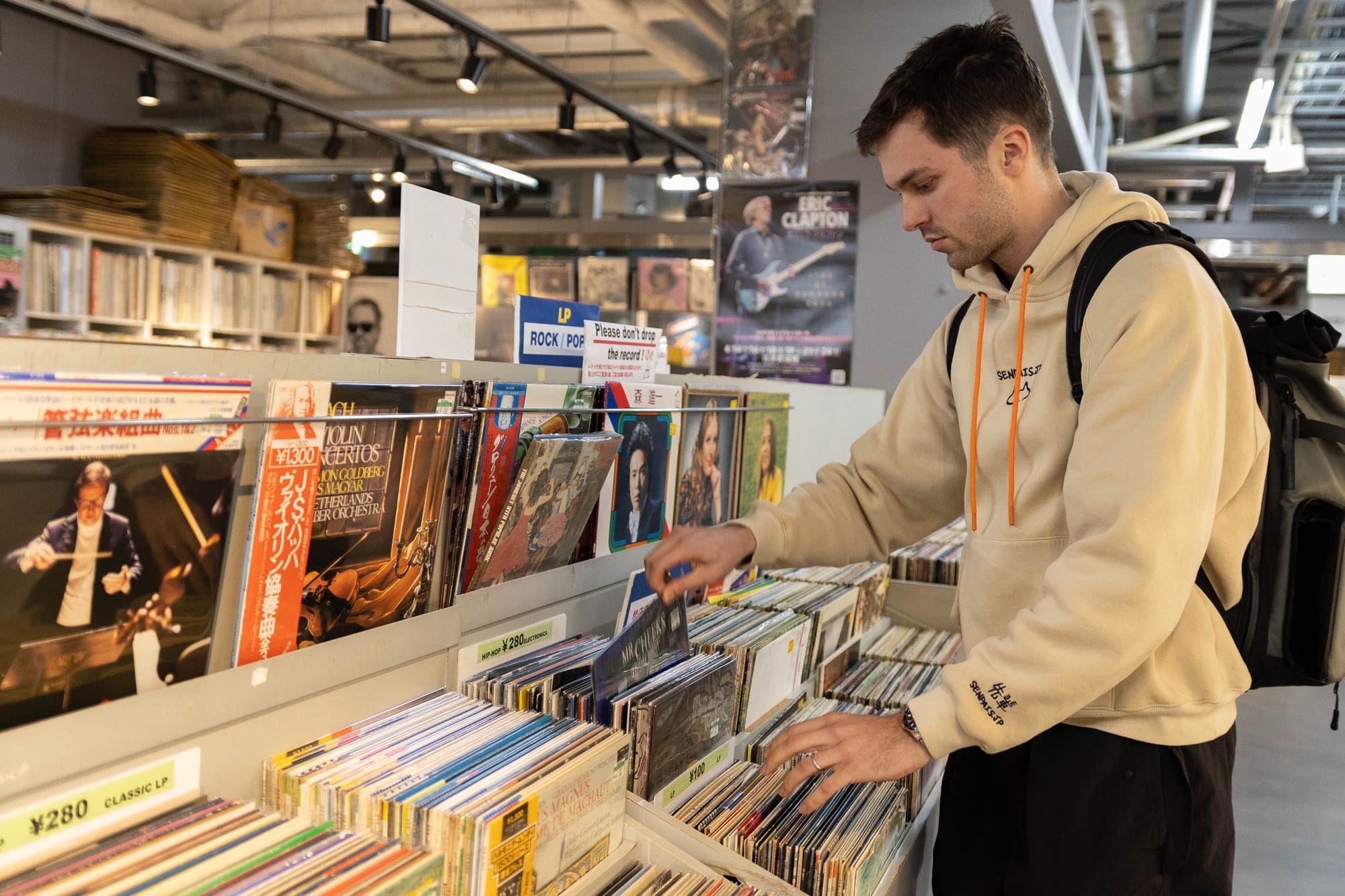 A young man in Japan looking through stacks of retro vinyls at a shop