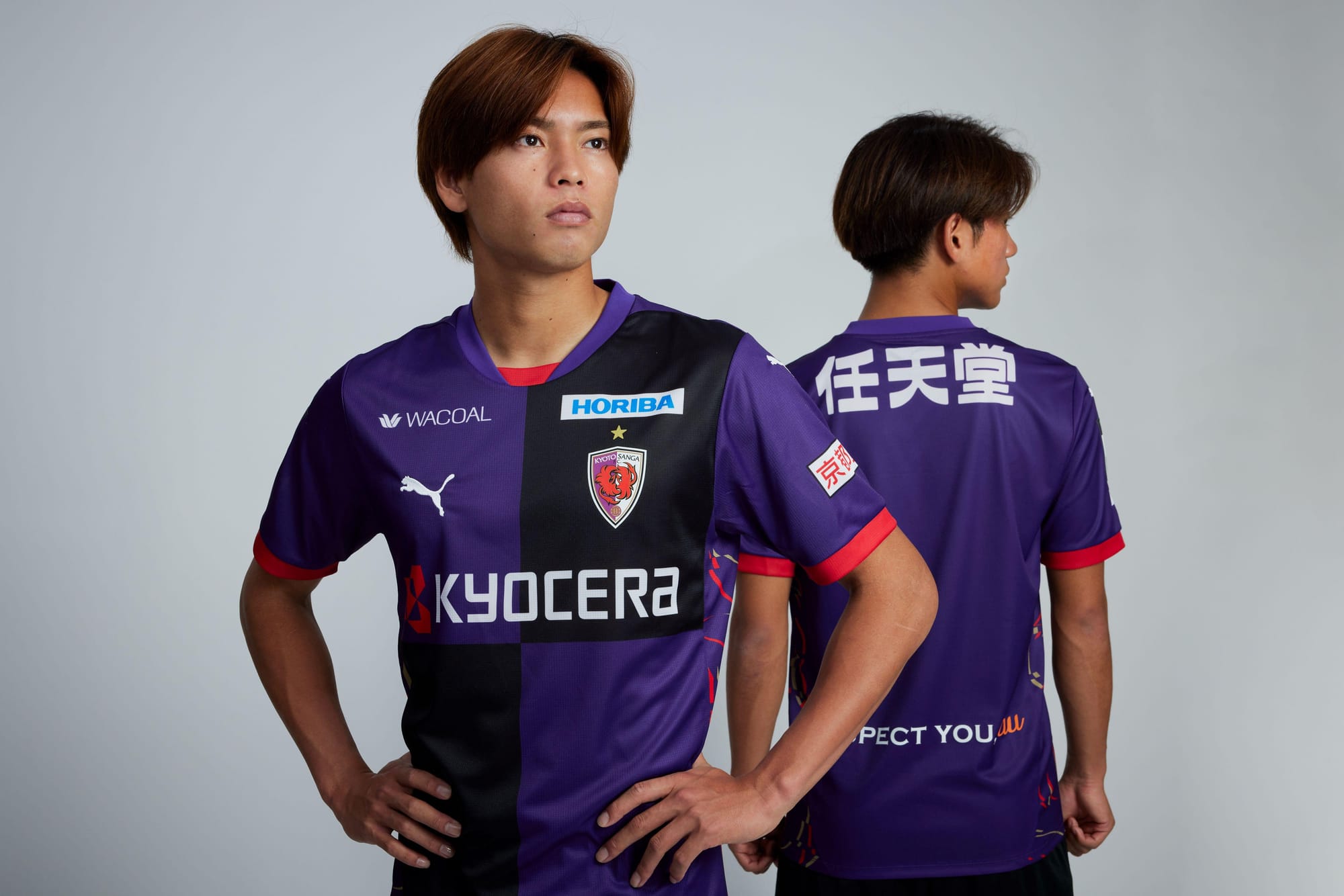 Two men in Kyoto Sanga soccer jerseys with sponsor logos