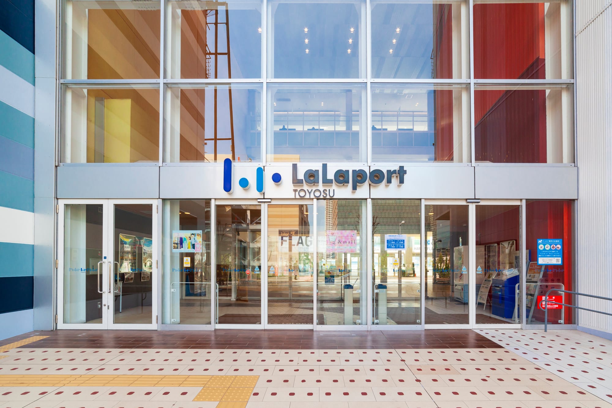 Entrance of LaLaport Toyosu mall with glass doors, colorful interior.