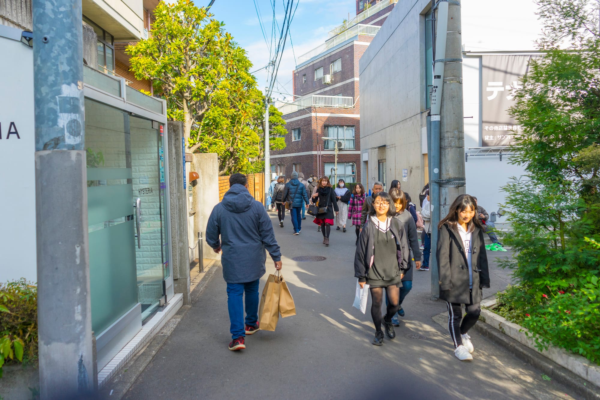 People walk along Keshita-Dori lined with buildings and greenery.