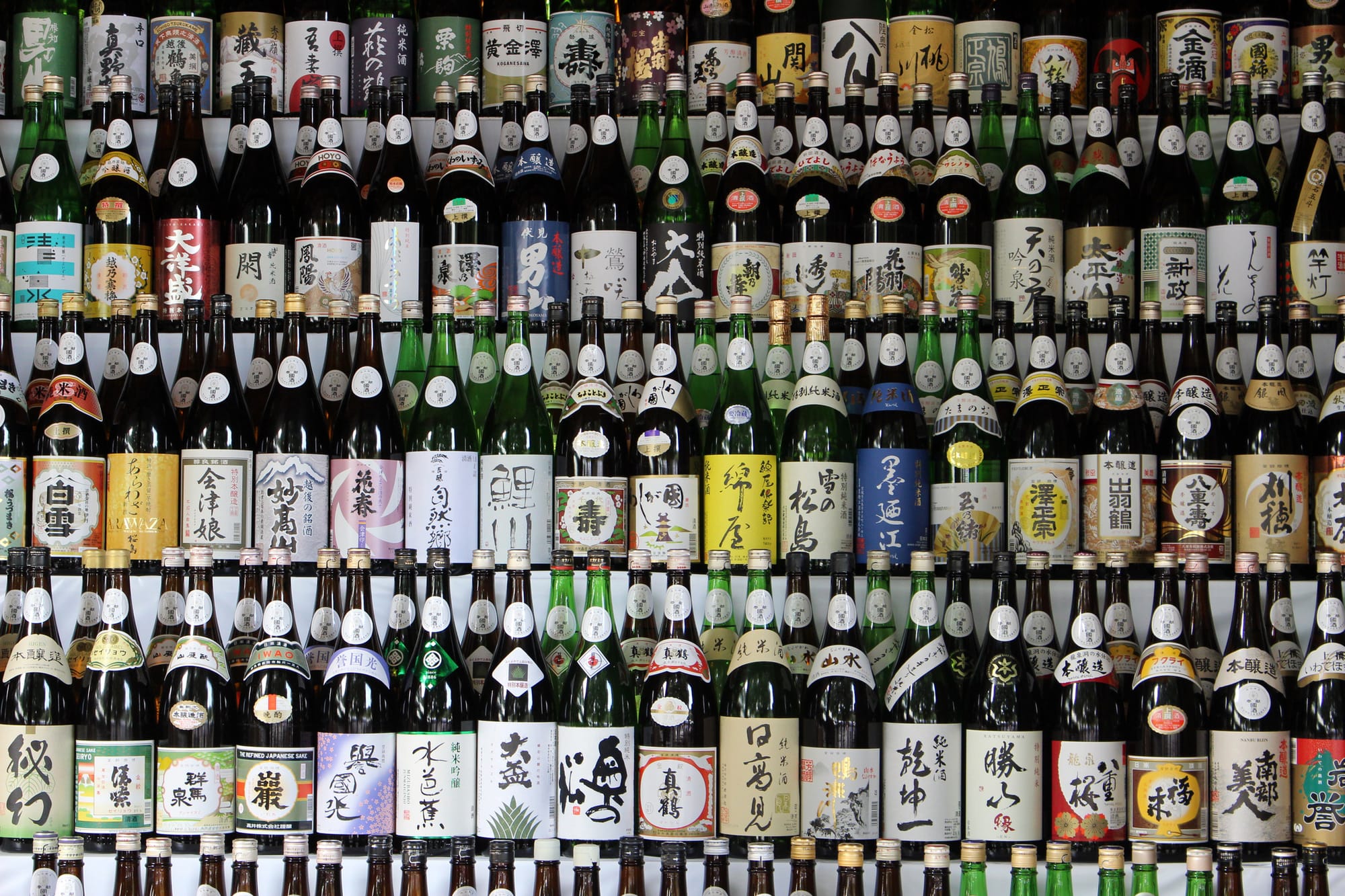 Rows of colorful Japanese sake bottles with various labels are displayed on shelves