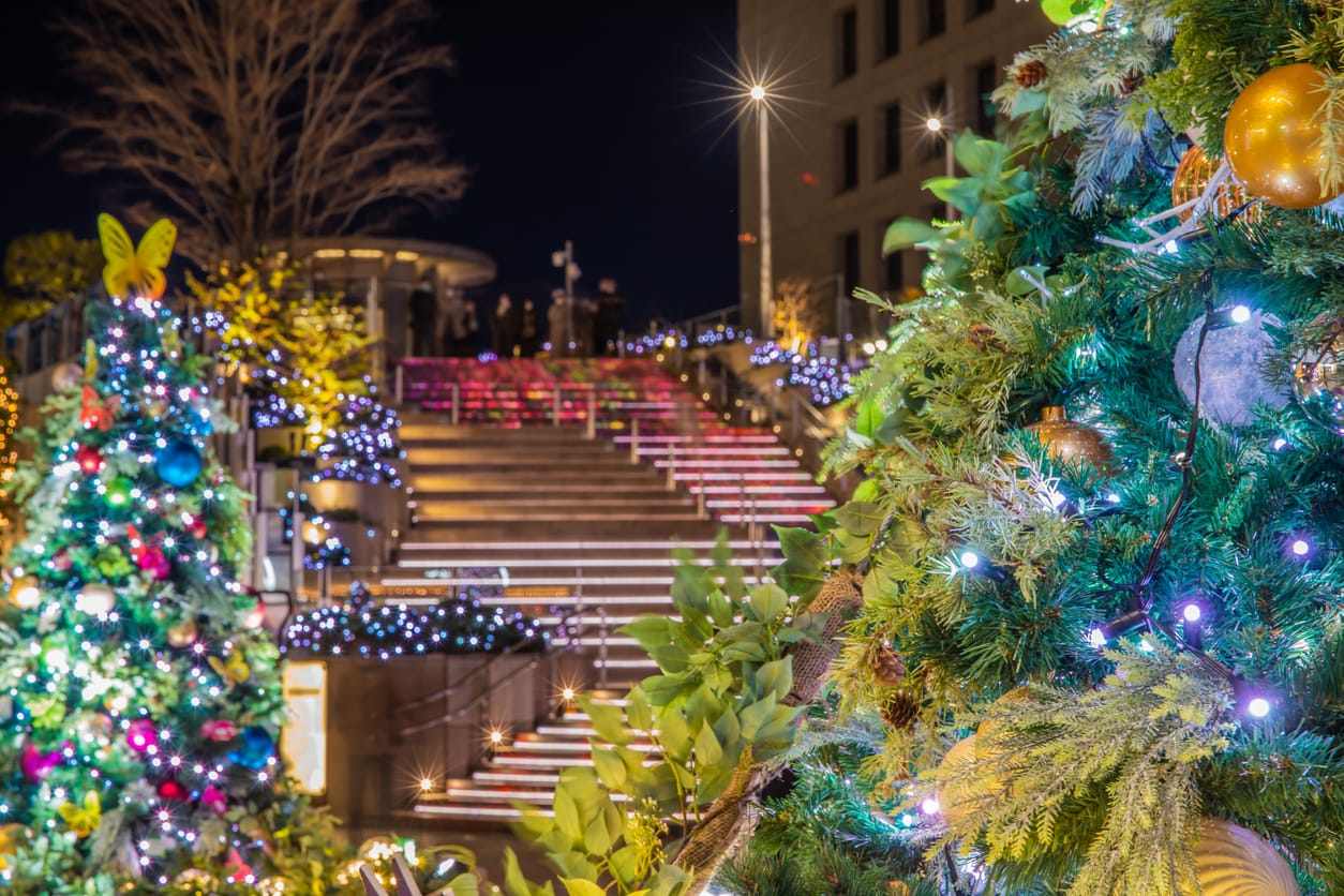 Festive outdoor scene at Tokyo Midtown Hibiya with illuminated Christmas trees, colorful decorations.