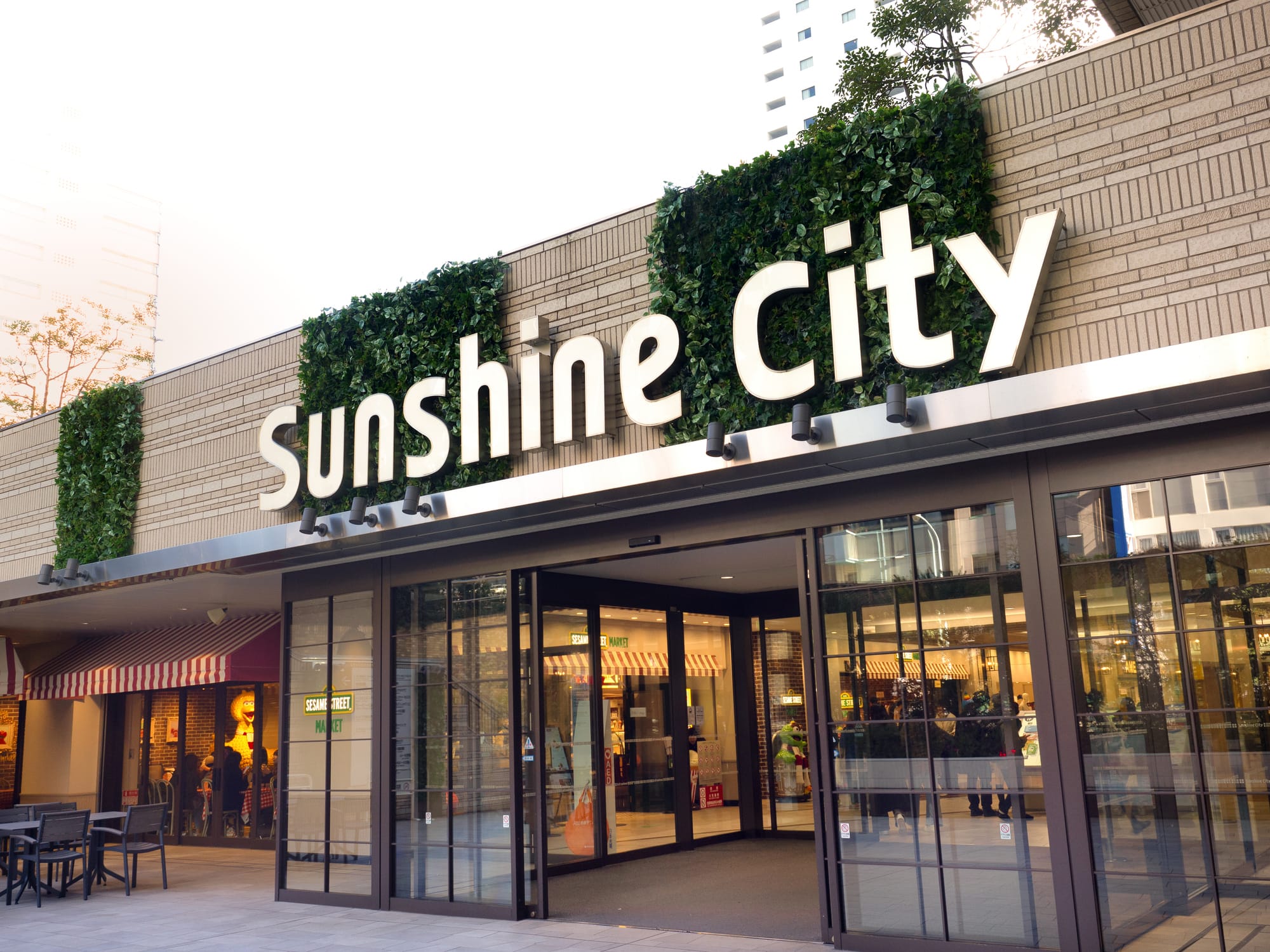 Entrance of Sunshine City mall with greenery on the brick facade.