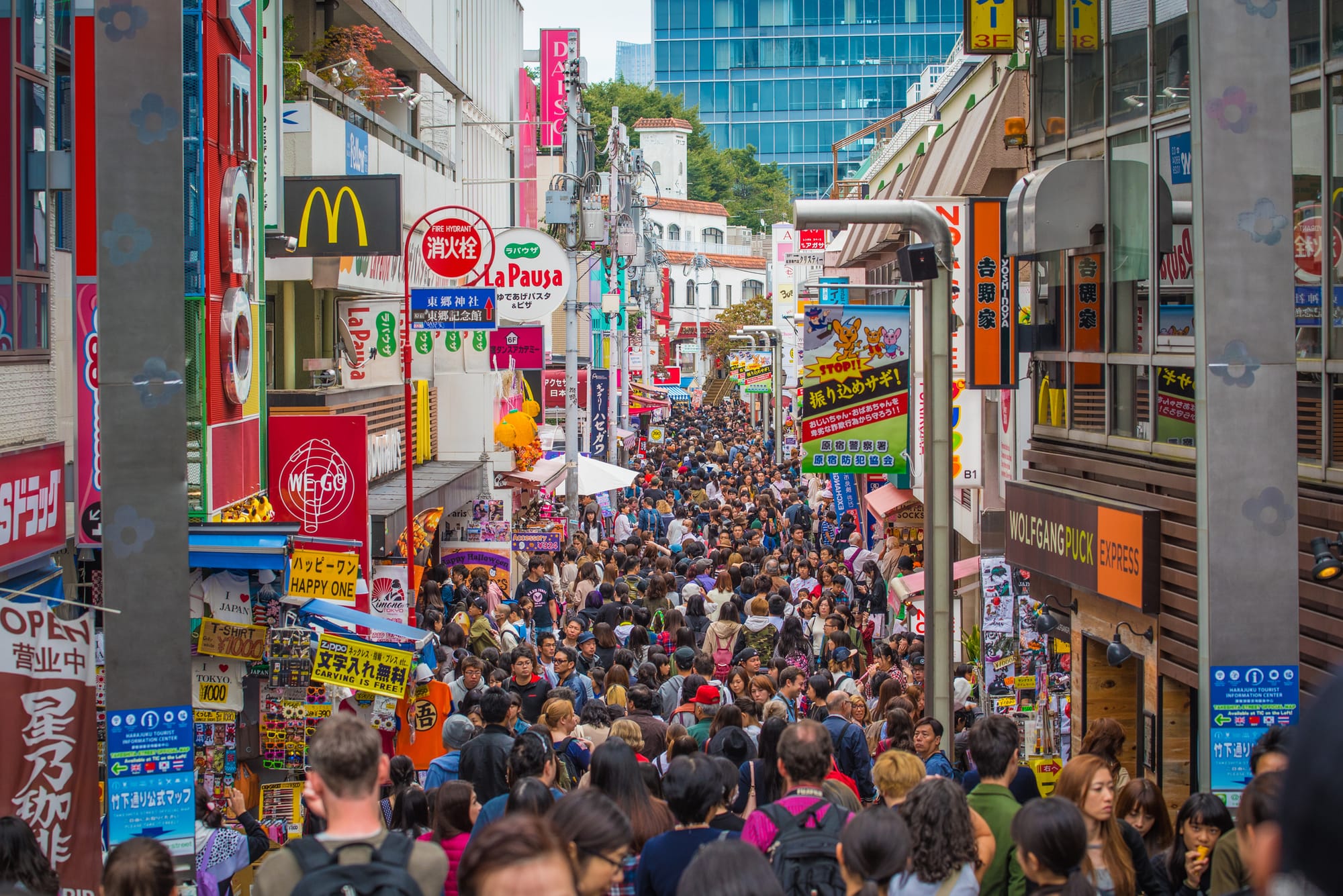 Crowded street of Takeshita, Harajuku, with colorful shop signs.