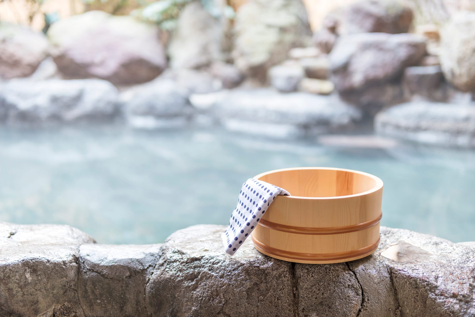 An outdoor onsen in japan with a bucket and towel.