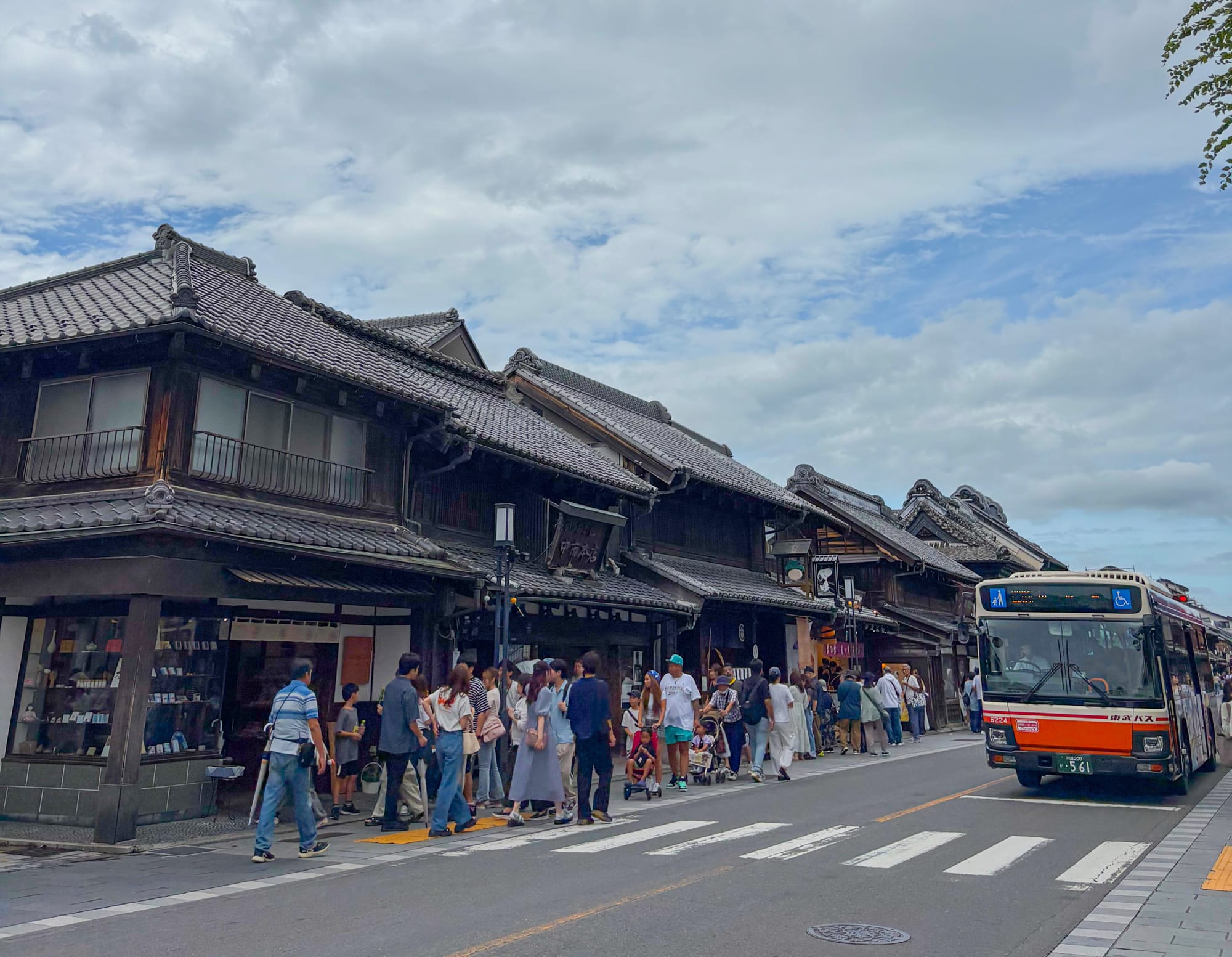 People walk along the Kawagoe Ichibangai Street, with traditional wooden buildings.