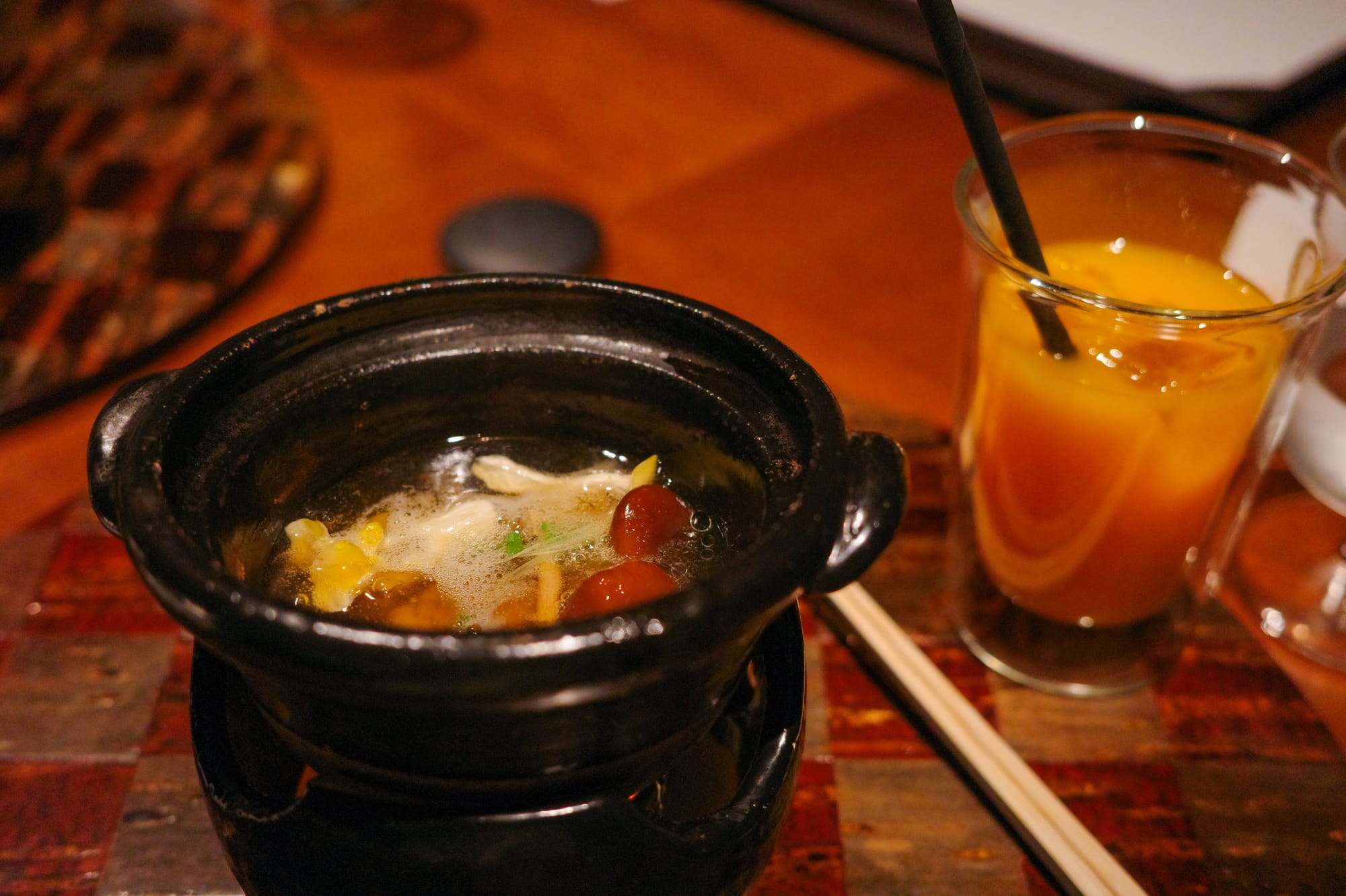 A steaming pot of soup with mushrooms, corn, herbs