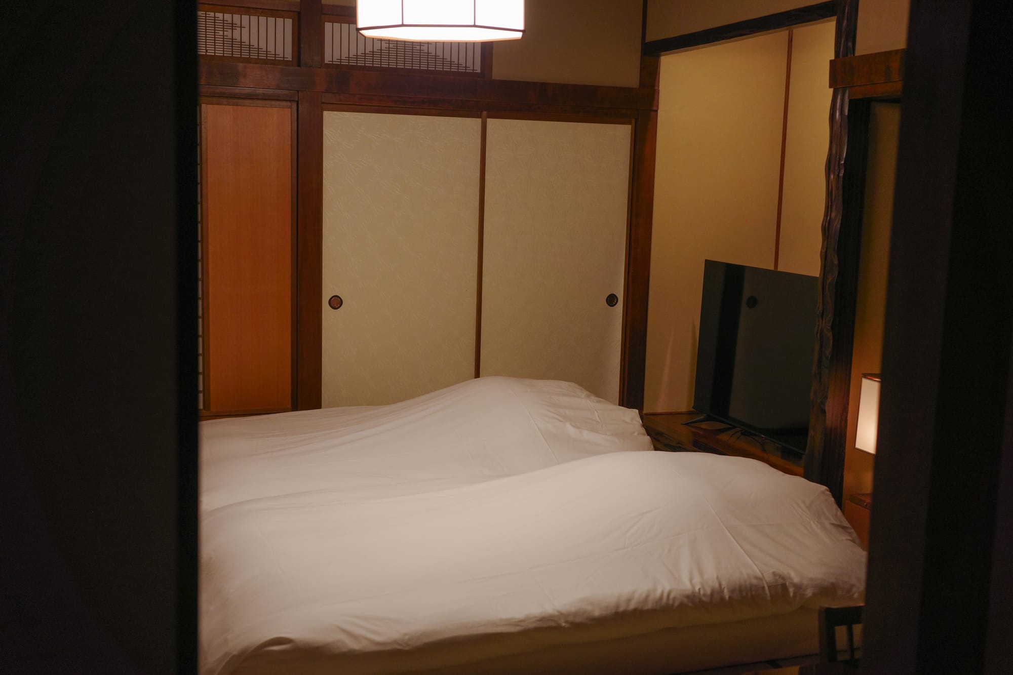 Dimly lit room with two white futons on the floor in a traditional Ryokan