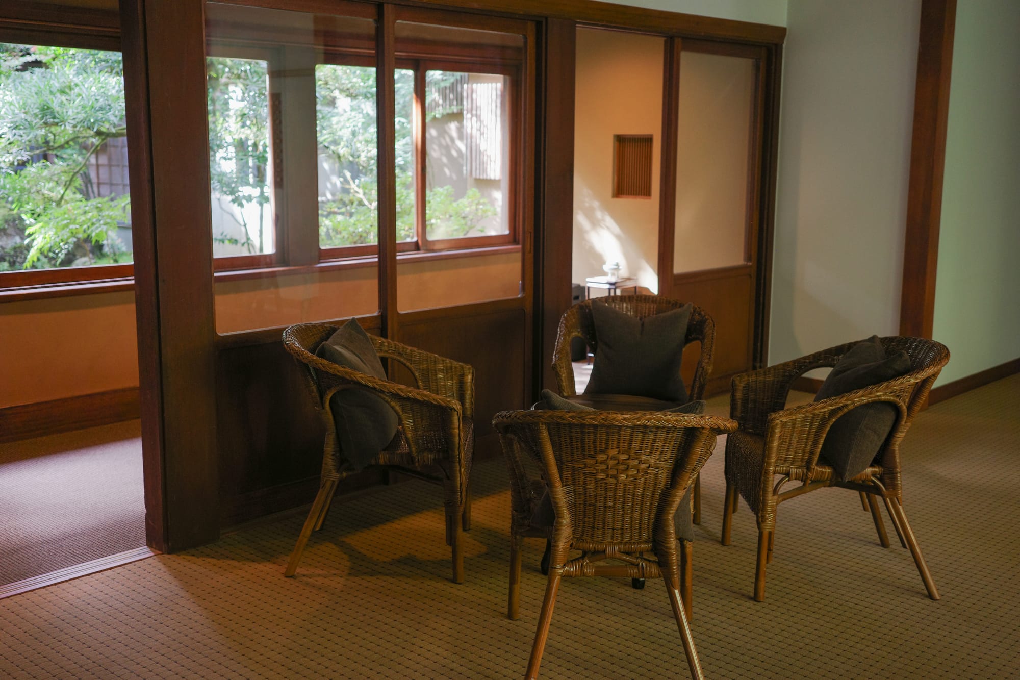 Wicker chairs and a small table in a dimly lit room with carpet.