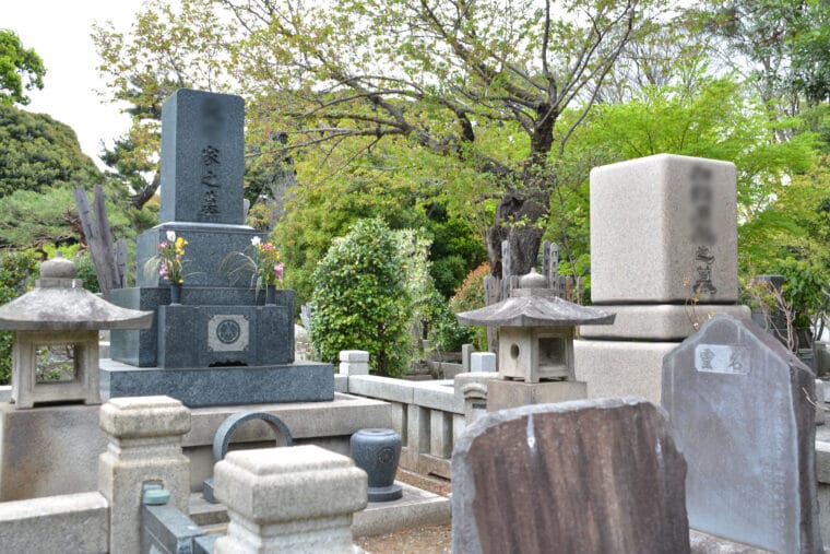 Various gravestones, including one with flowers as offerings, at a cemetery in Japan