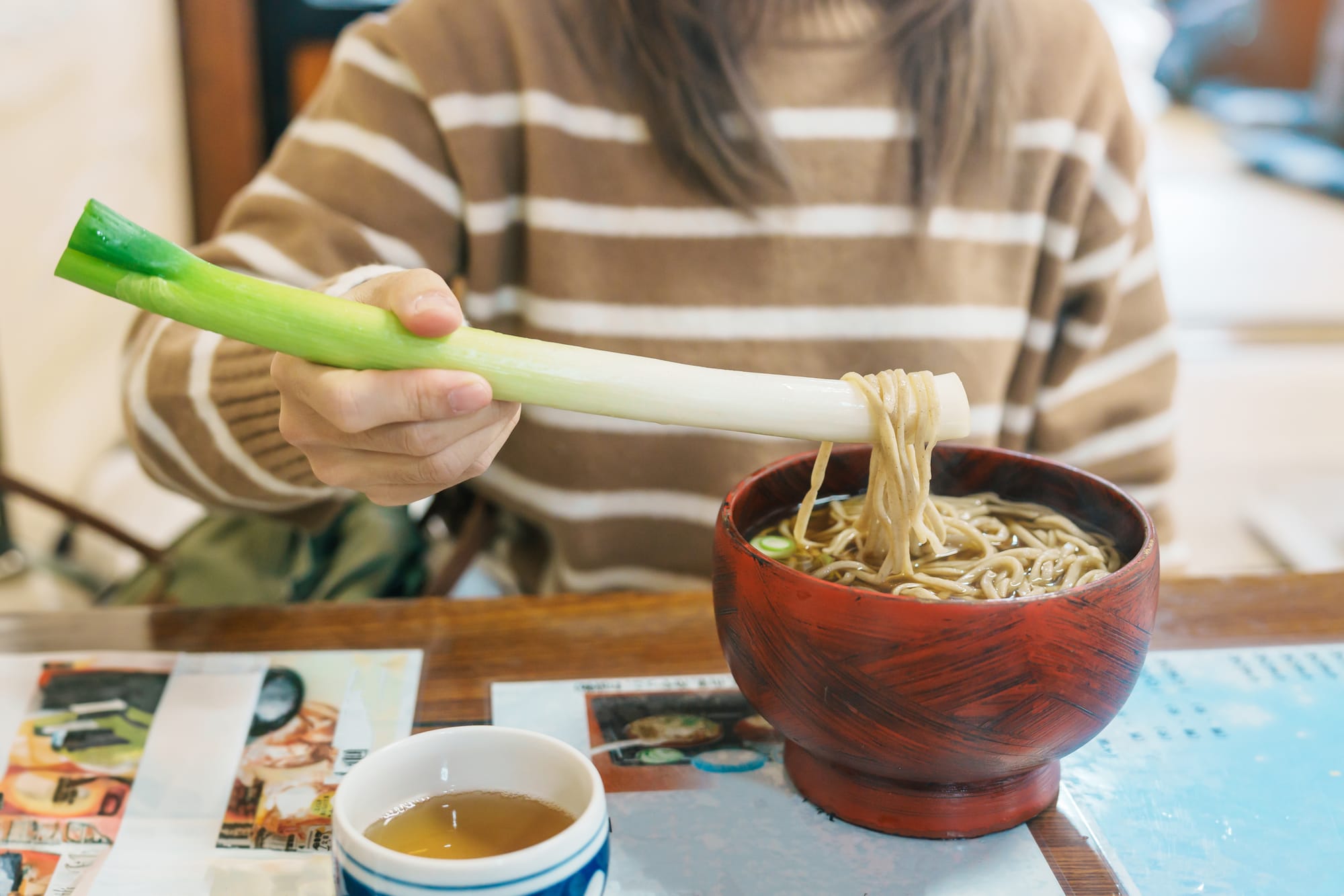 Bowl of Ouchi-juku Negi Soba noodles served with a green onion stalk as an edible utensil in Fukushima