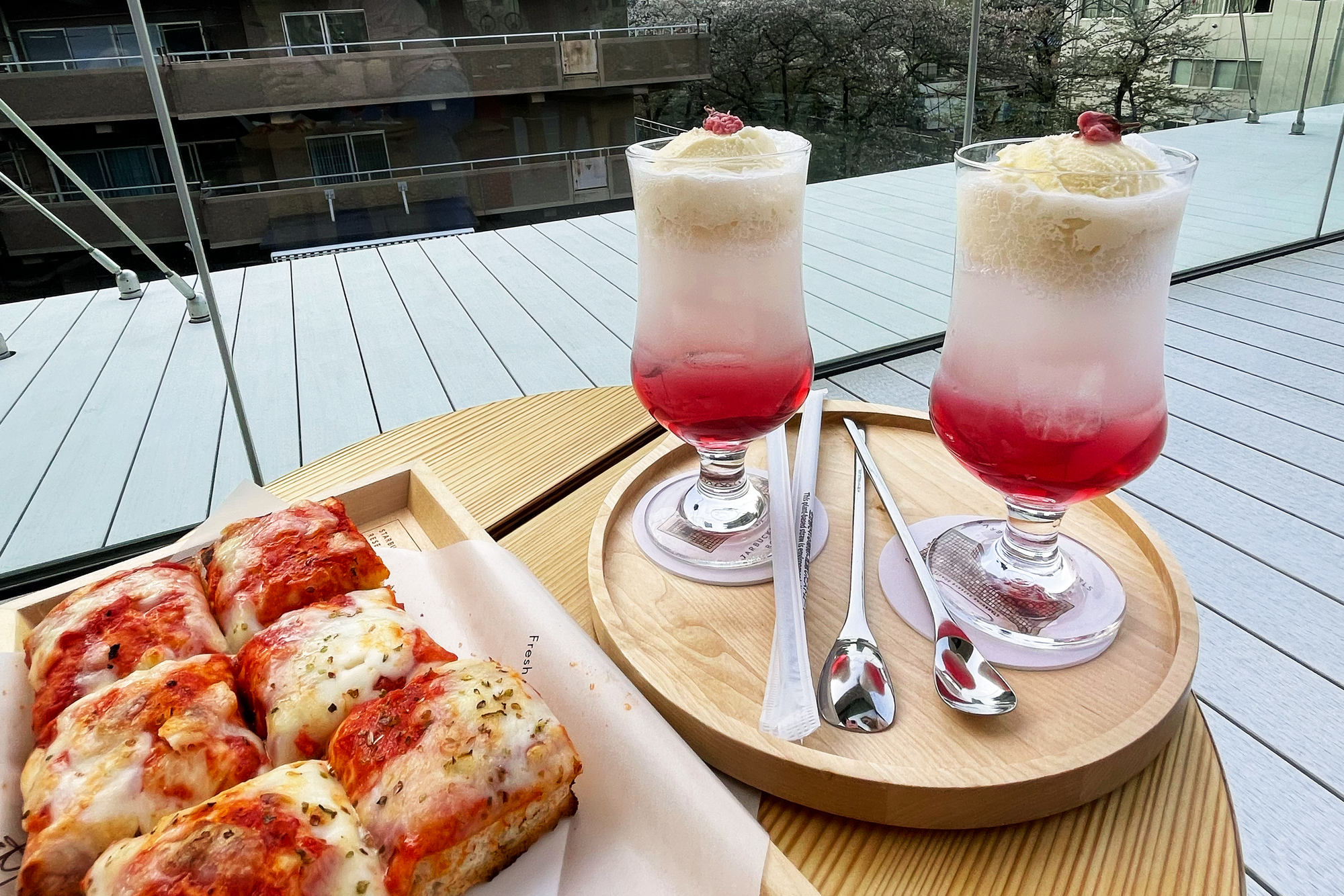 Square slices of pizza sitting next to two float drinks that are sakura themed.